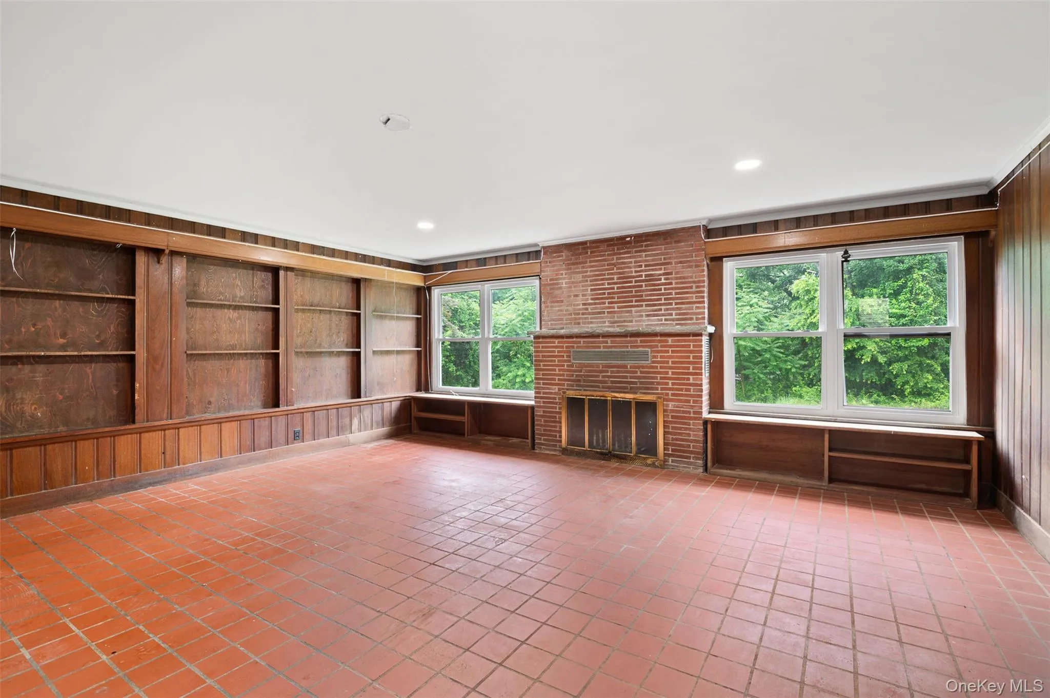 Unfurnished living room with wood walls, a fireplace, light tile patterned floors, recessed lighting, and built in shelves Unfurnished living room with wood walls, a fireplace, light tile patterned floors, recessed lighting, and built in shelves