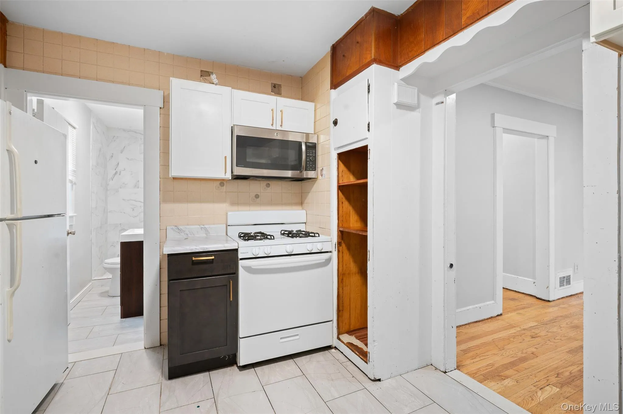 Kitchen featuring white appliances, light countertops, tile walls, white cabinets, and decorative backsplash Kitchen featuring white appliances, light countertops, tile walls, white cabinets, and decorative backsplash