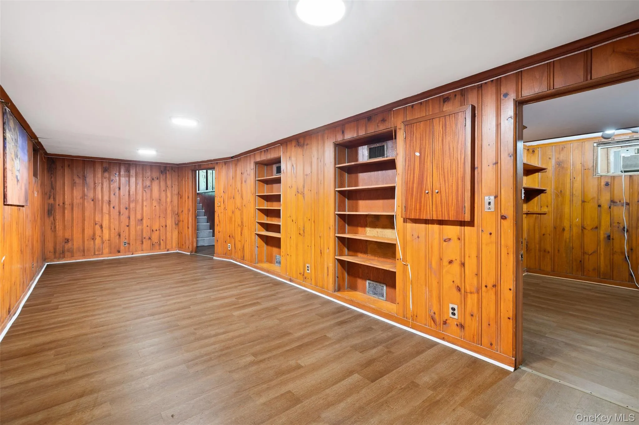 Spare room with wood walls, wood finished floors, and built in shelves Spare room with wood walls, wood finished floors, and built in shelves