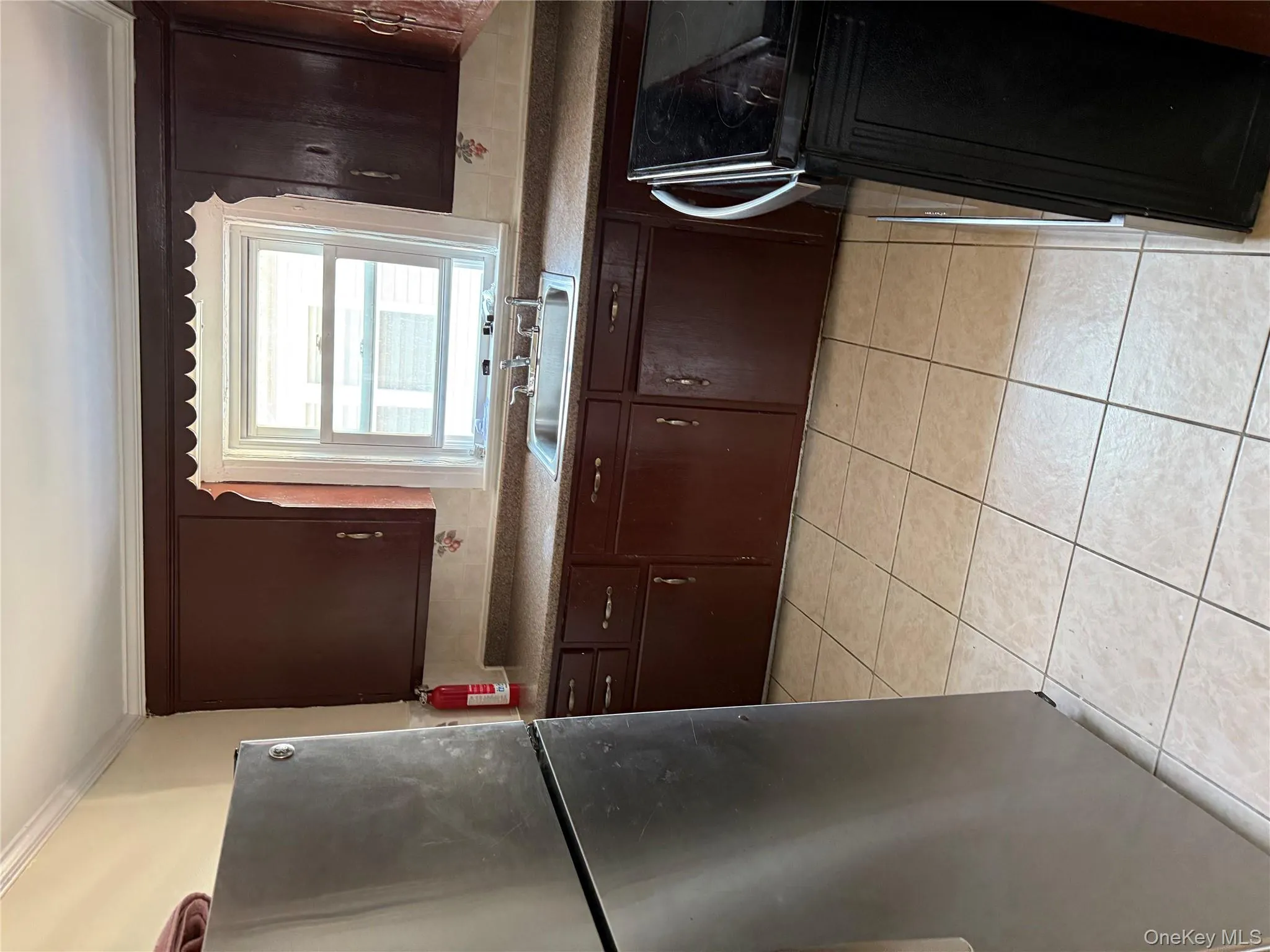 Kitchen with fridge, dark brown cabinetry, range, light tile patterned floors, and ornamental molding Kitchen with fridge, dark brown cabinetry, range, light tile patterned floors, and ornamental molding