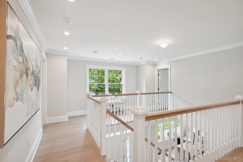 Hall with ornamental molding, light wood-type flooring, an upstairs landing, and recessed lighting Hall with ornamental molding, light wood-type flooring, an upstairs landing, and recessed lighting