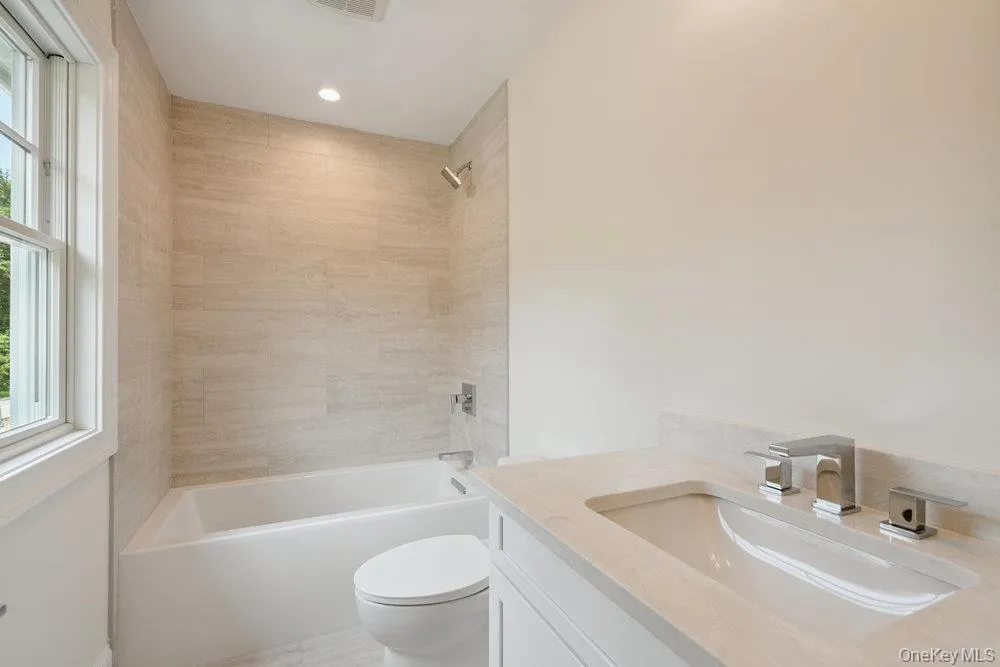 Bathroom with healthy amount of natural light, vanity, shower / bathtub combination, and recessed lighting Bathroom with healthy amount of natural light, vanity, shower / bathtub combination, and recessed lighting