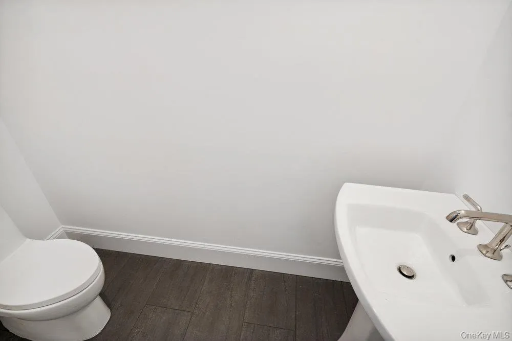 Half bathroom with dark wood-style floors and baseboards Half bathroom with dark wood-style floors and baseboards
