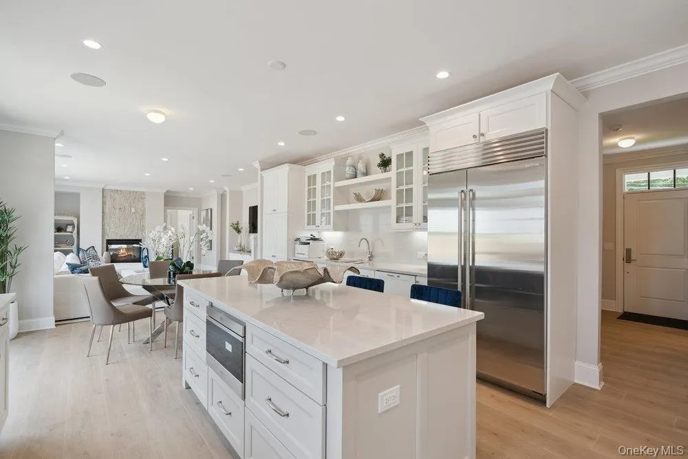 Kitchen with crown molding, white cabinetry, open shelves, stainless steel appliances, and open floor plan Kitchen with crown molding, white cabinetry, open shelves, stainless steel appliances, and open floor plan