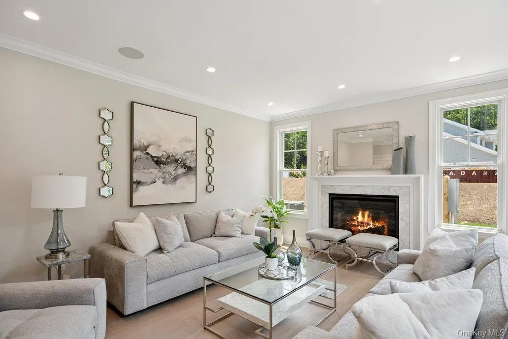 Living room with crown molding, recessed lighting, wood finished floors, and a high end fireplace Living room with crown molding, recessed lighting, wood finished floors, and a high end fireplace