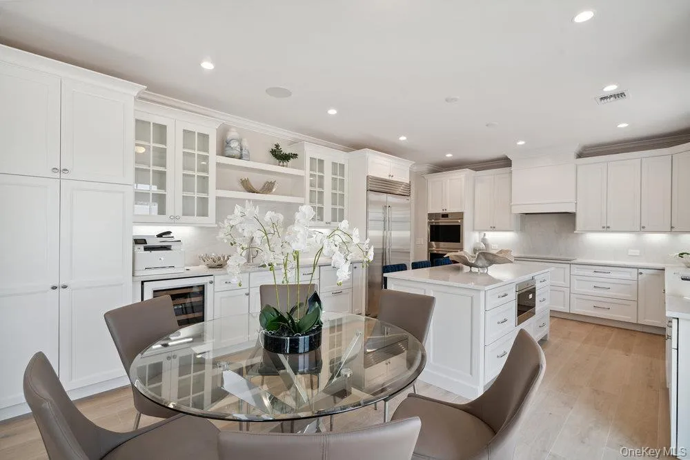 Kitchen featuring open shelves, decorative backsplash, white cabinets, light wood-style floors, and stainless steel appliances Kitchen featuring open shelves, decorative backsplash, white cabinets, light wood-style floors, and stainless steel appliances