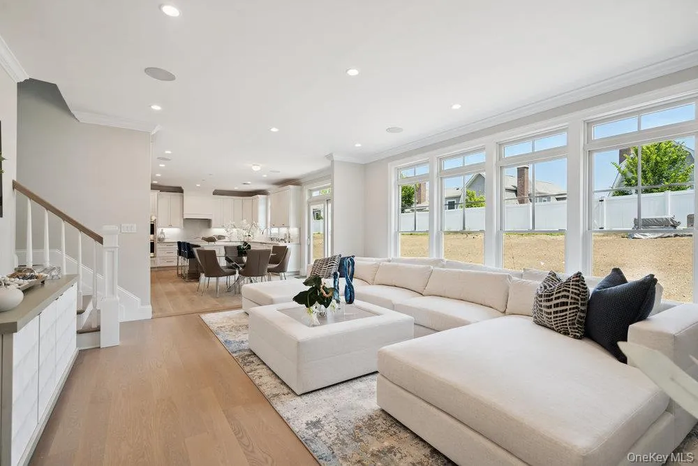 Living area featuring light wood-style floors, ornamental molding, stairway, and recessed lighting Living area featuring light wood-style floors, ornamental molding, stairway, and recessed lighting