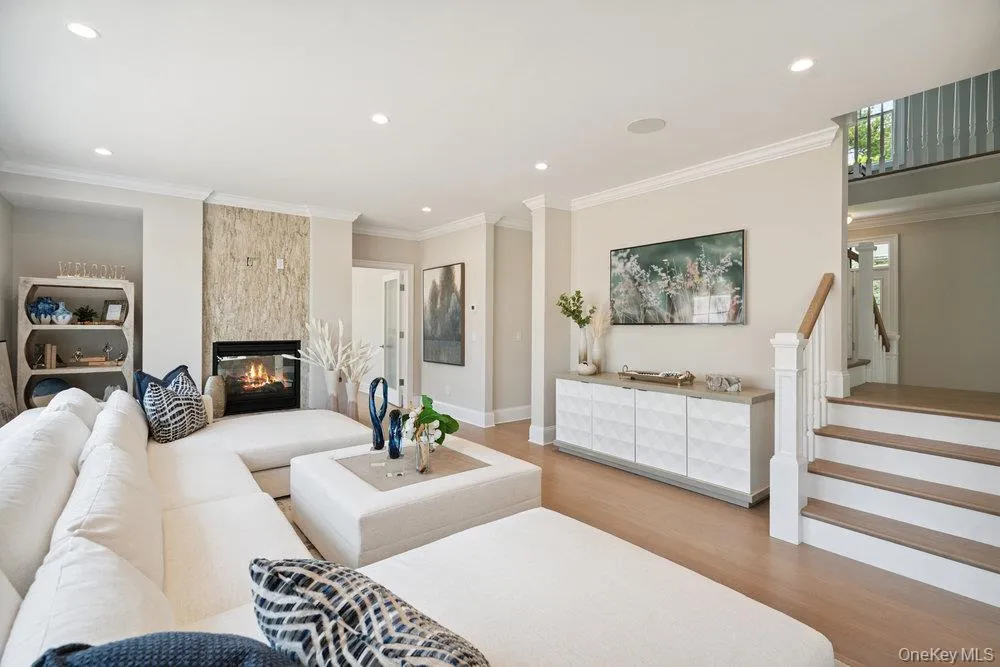 Living room featuring light wood-style floors, a multi sided fireplace, crown molding, recessed lighting, and stairway Living room featuring light wood-style floors, a multi sided fireplace, crown molding, recessed lighting, and stairway