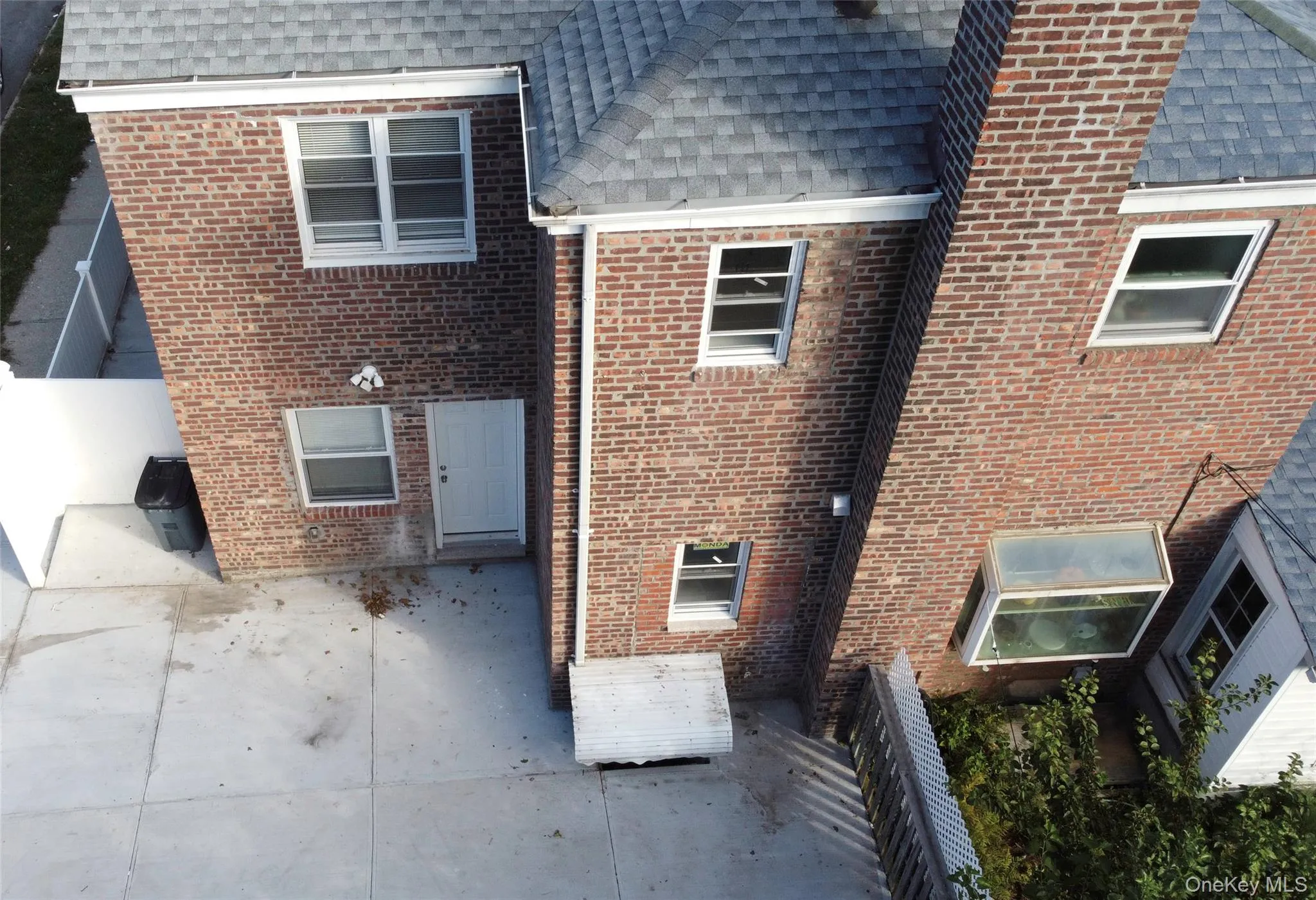 View of side of property featuring a shingled roof and brick siding View of side of property featuring a shingled roof and brick siding