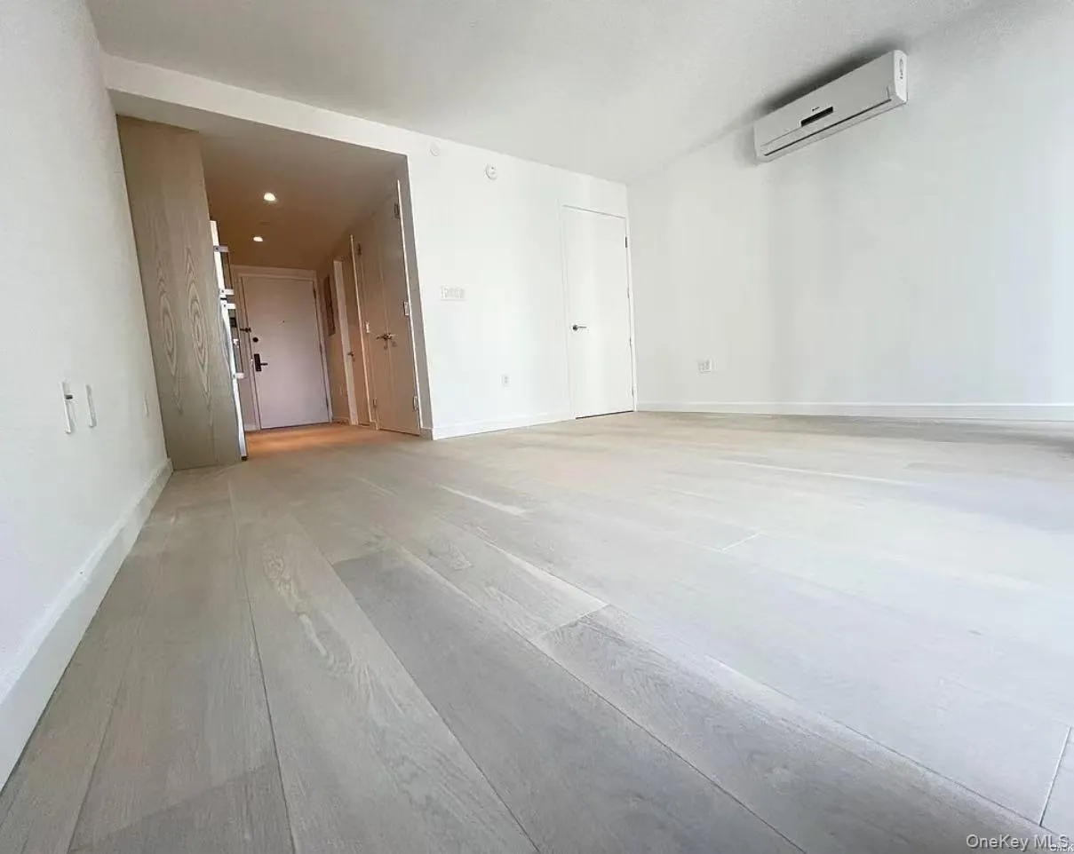 Empty room featuring a wall mounted air conditioner and light wood-type flooring Empty room featuring a wall mounted air conditioner and light wood-type flooring