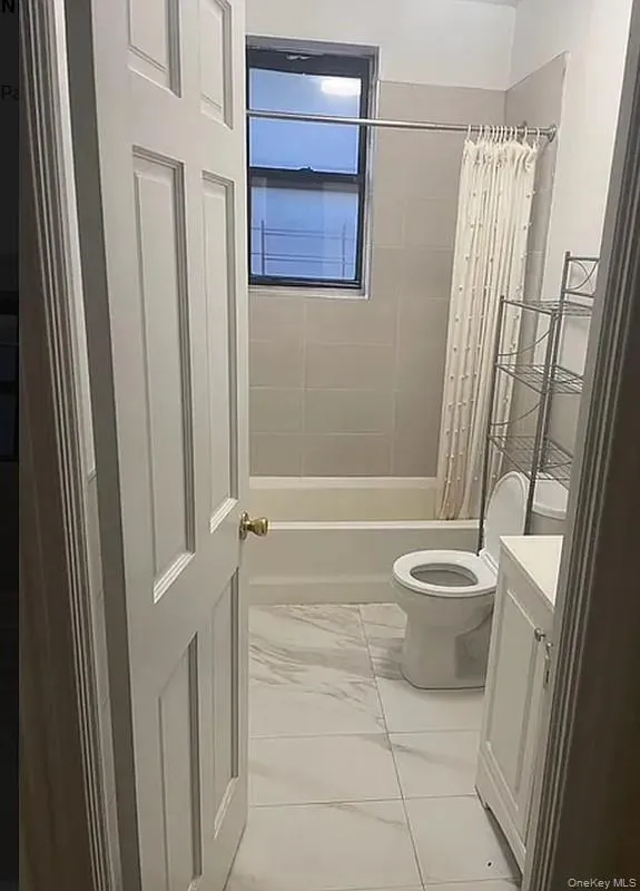 Bathroom with shower / bathtub combination with curtain, vanity, and light marble finish flooring Bathroom with shower / bathtub combination with curtain, vanity, and light marble finish flooring