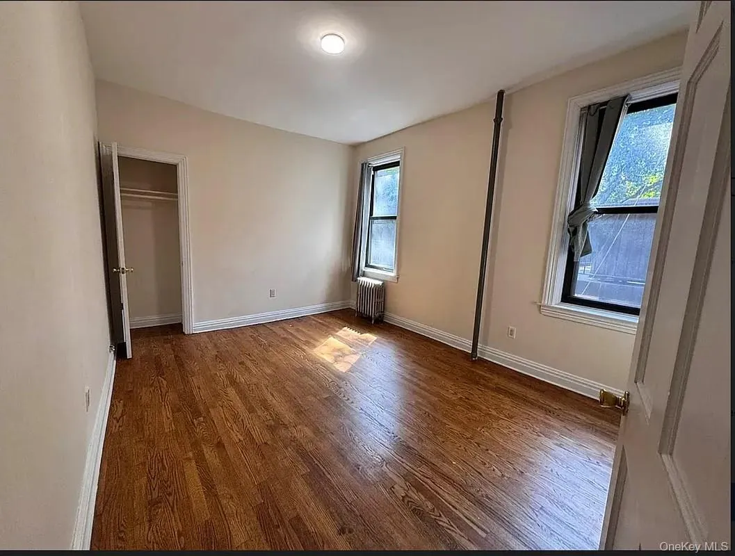 Unfurnished bedroom with dark wood finished floors, radiator heating unit, and a closet Unfurnished bedroom with dark wood finished floors, radiator heating unit, and a closet