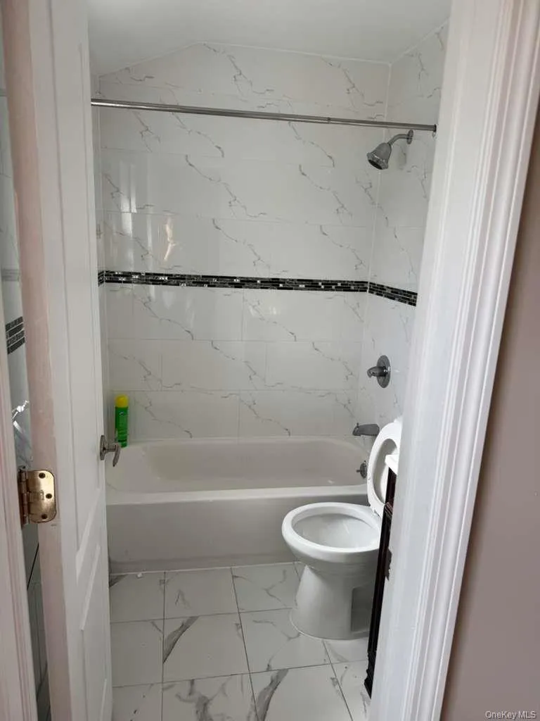 Bathroom with light marble finish flooring and bathtub / shower combination Bathroom with light marble finish flooring and bathtub / shower combination