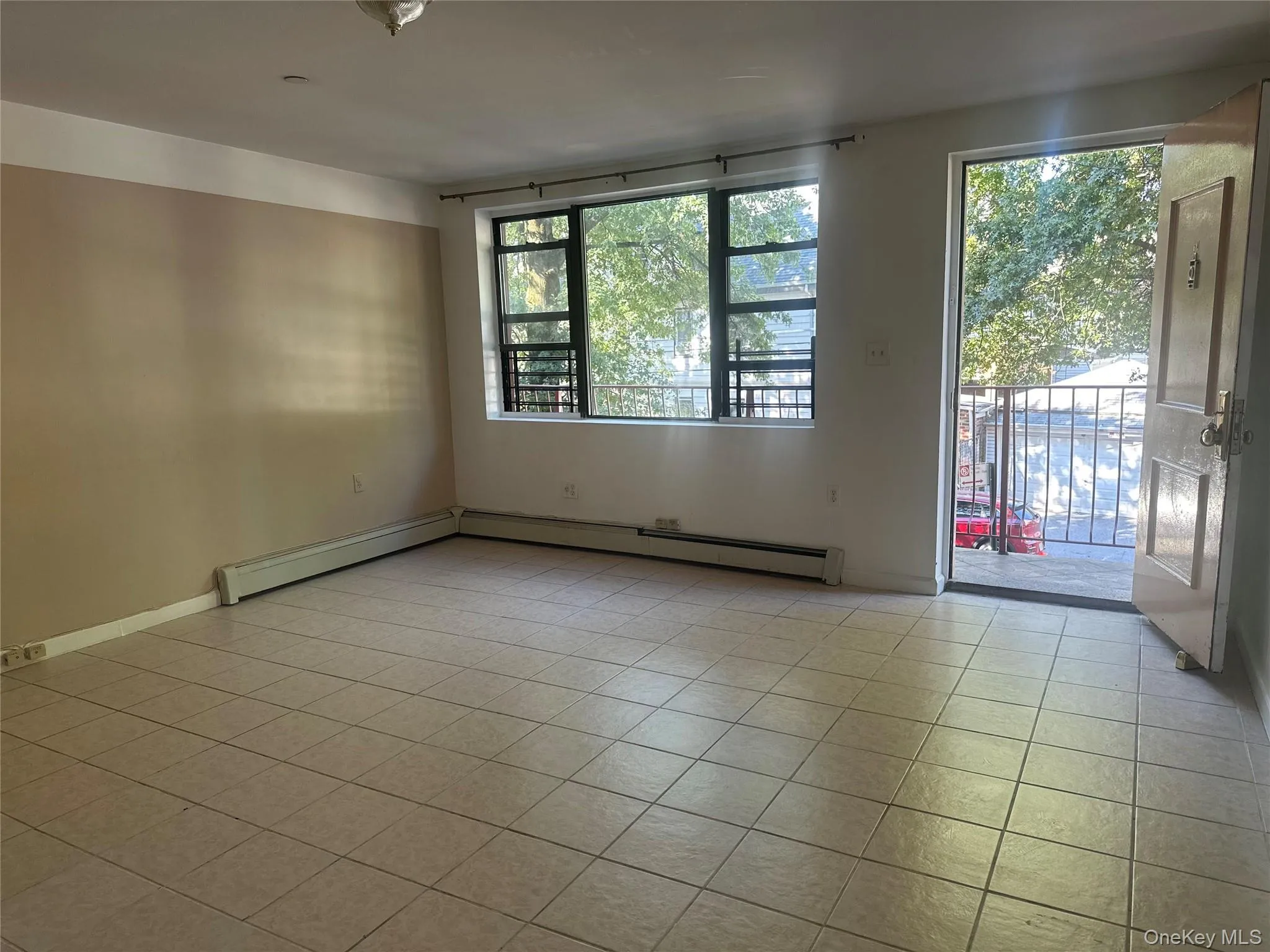 Unfurnished room with light tile patterned floors and baseboard heating Unfurnished room with light tile patterned floors and baseboard heating