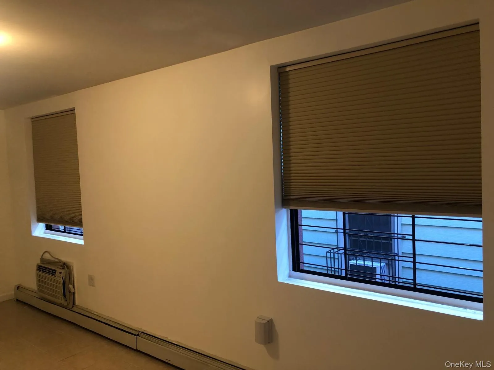 Tiled empty room with a baseboard radiator, healthy amount of natural light, and a wall mounted AC Tiled empty room with a baseboard radiator, healthy amount of natural light, and a wall mounted AC