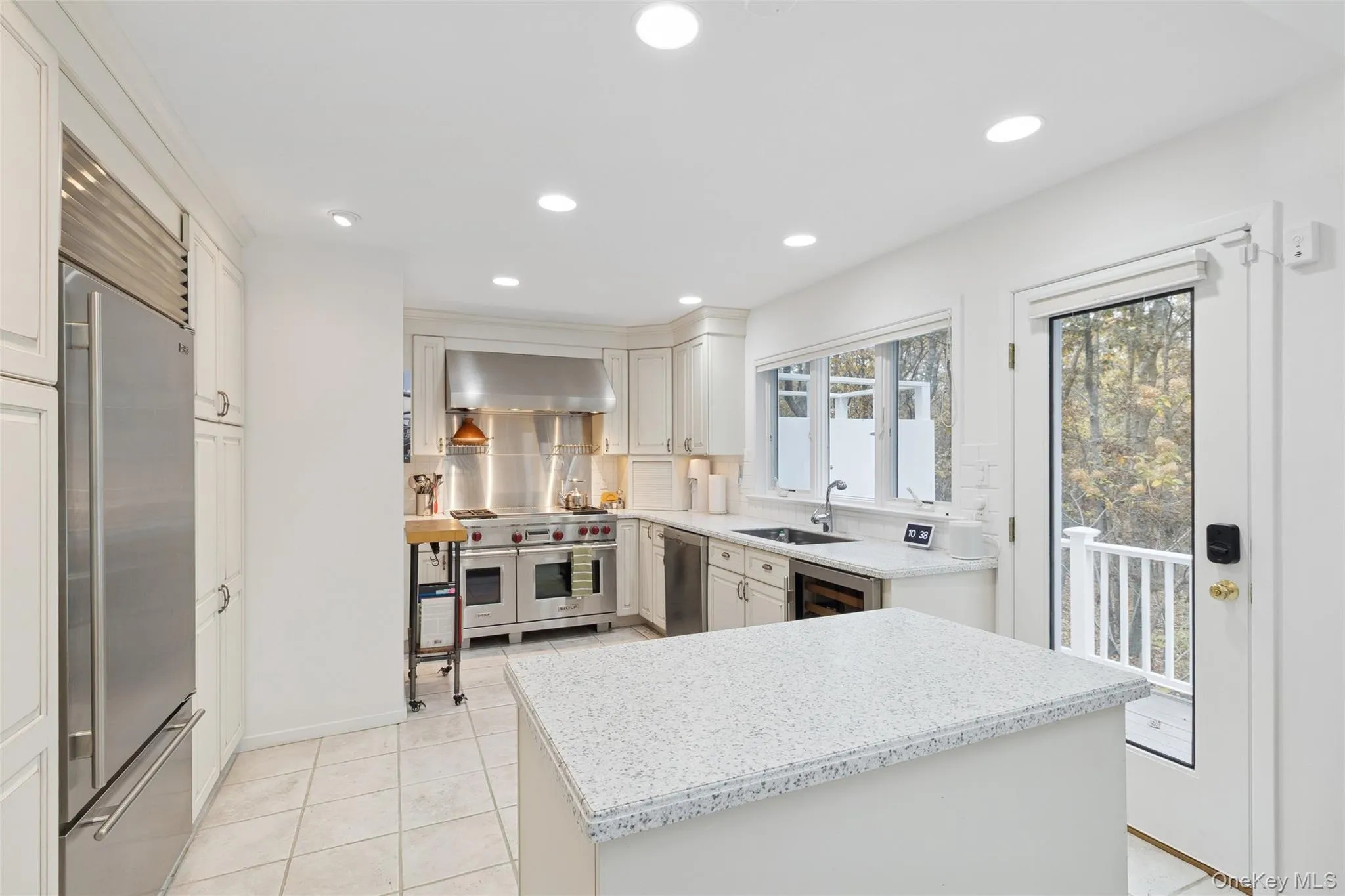 Kitchen featuring premium appliances, light tile patterned floors, white cabinets, wall chimney range hood, and recessed lighting Kitchen featuring premium appliances, light tile patterned floors, white cabinets, wall chimney range hood, and recessed lighting