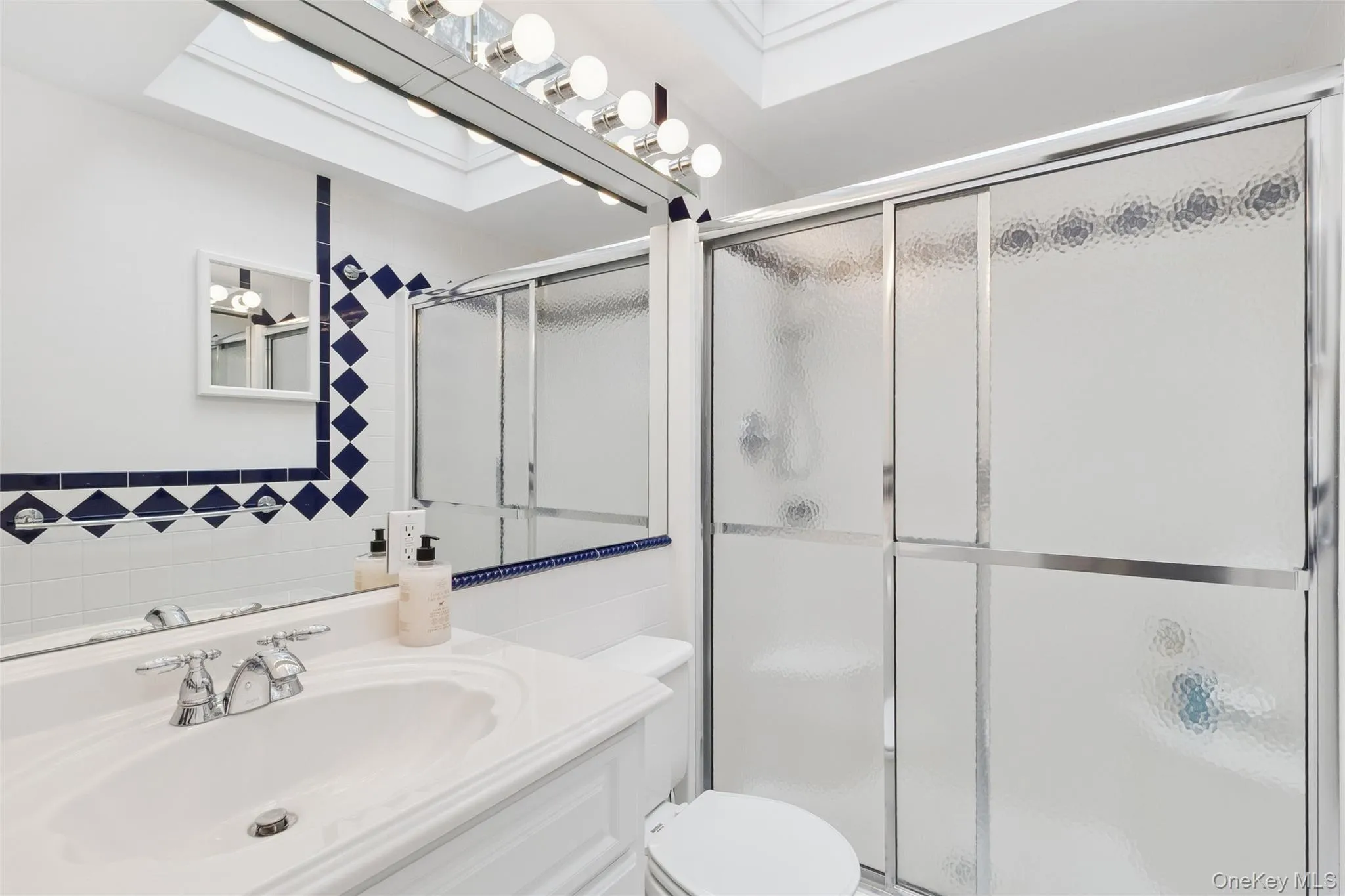 Bathroom with vanity, tile walls, and a shower stall Bathroom with vanity, tile walls, and a shower stall