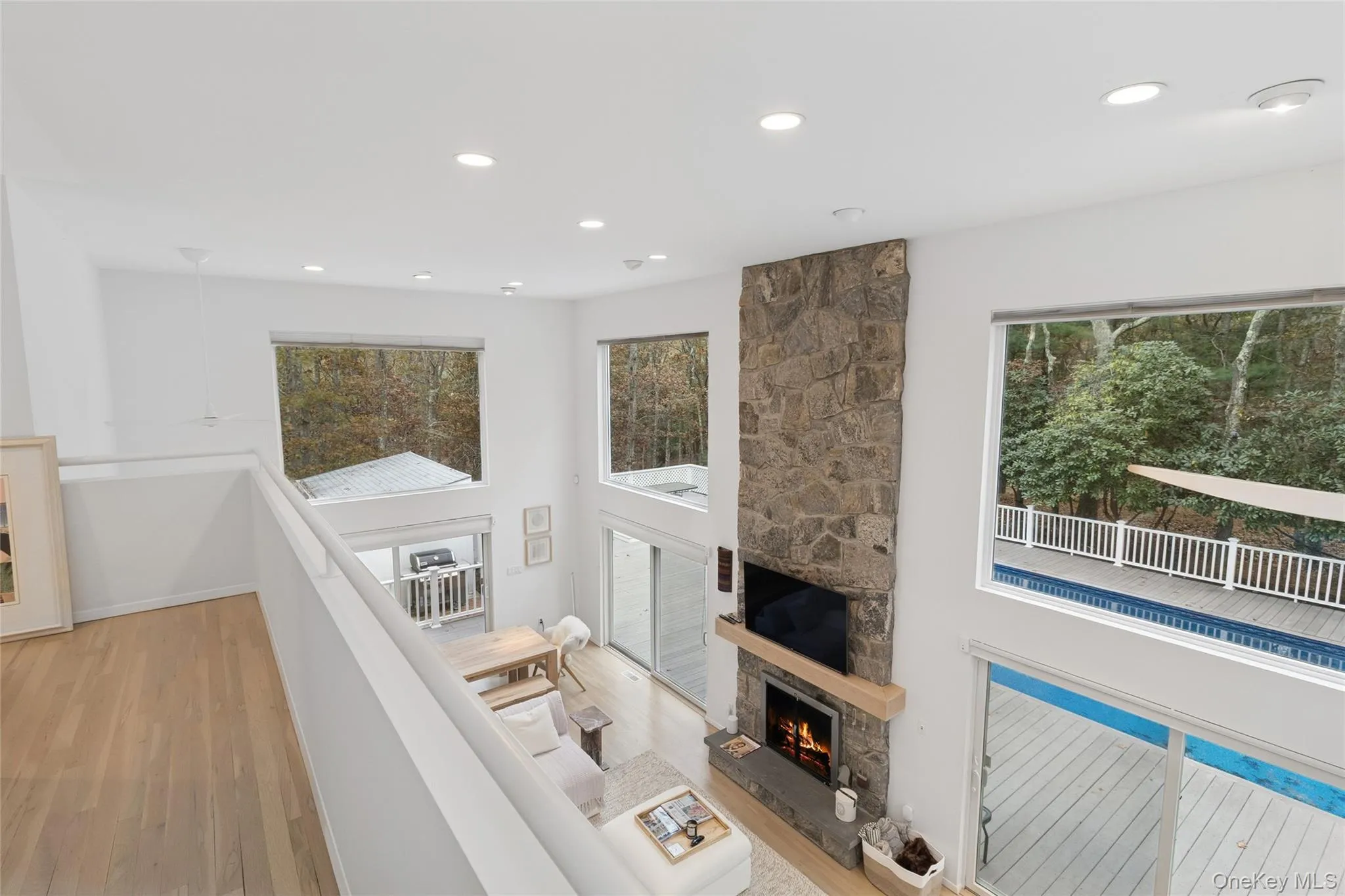 Living area featuring a fireplace, recessed lighting, a towering ceiling, and light wood-style flooring Living area featuring a fireplace, recessed lighting, a towering ceiling, and light wood-style flooring