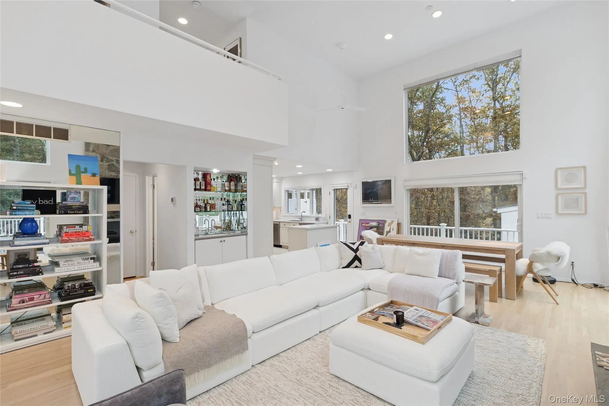 Living area featuring wood finished floors, a towering ceiling, recessed lighting, and plenty of natural light Living area featuring wood finished floors, a towering ceiling, recessed lighting, and plenty of natural light