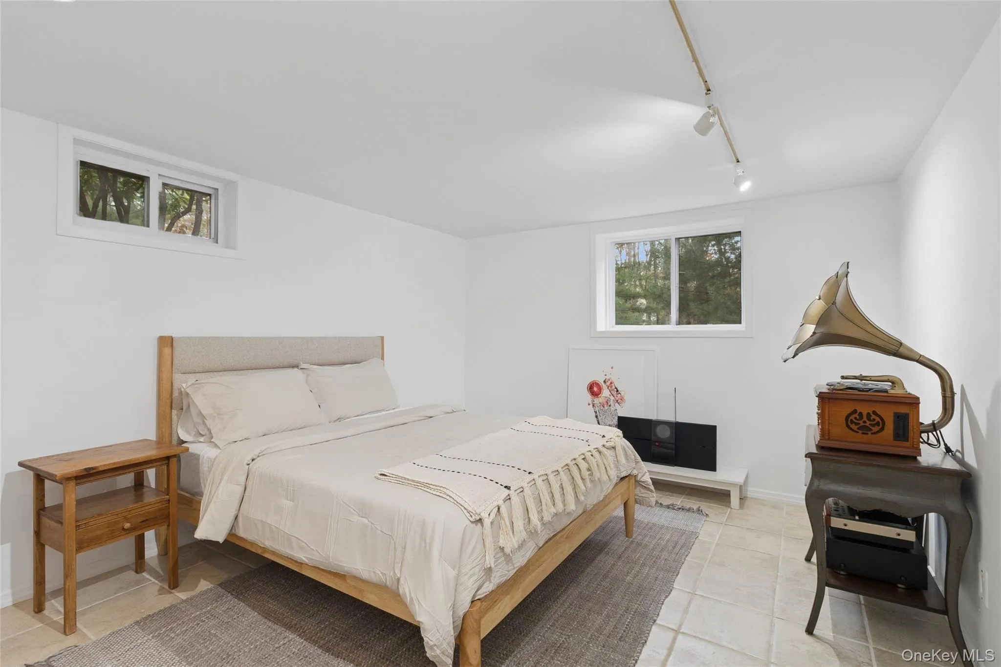Bedroom with rail lighting, multiple windows, and light tile patterned floors Bedroom with rail lighting, multiple windows, and light tile patterned floors