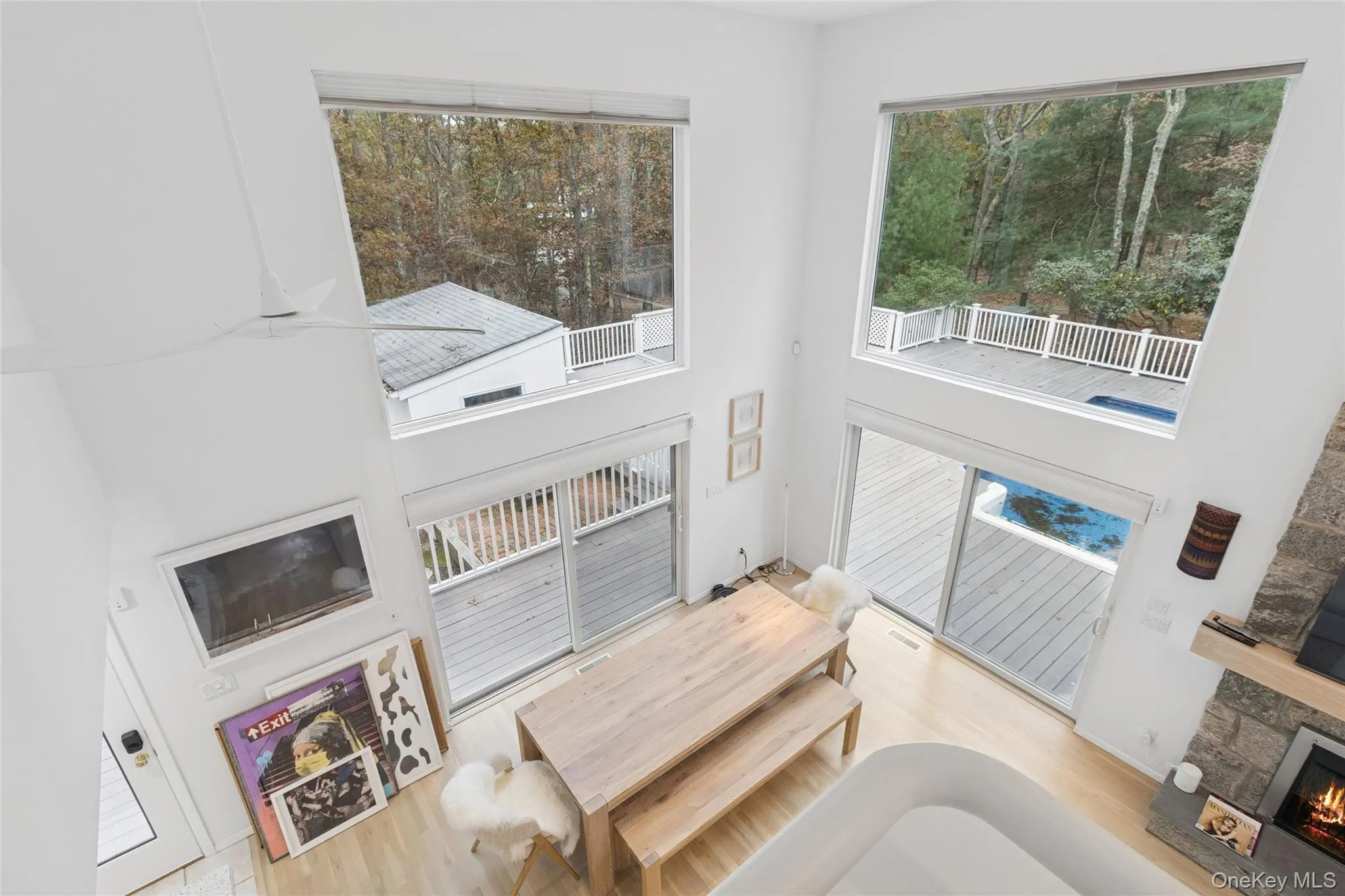 Living area with a high ceiling, wood finished floors, a stone fireplace, and plenty of natural light Living area with a high ceiling, wood finished floors, a stone fireplace, and plenty of natural light