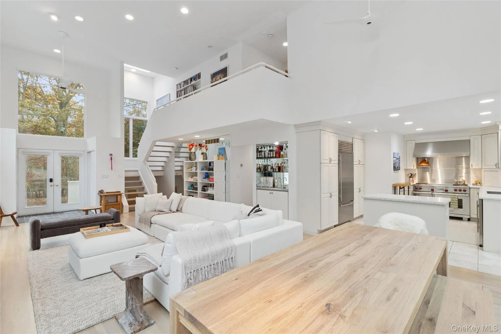 Living area with a towering ceiling, recessed lighting, french doors, stairway, and a bar Living area with a towering ceiling, recessed lighting, french doors, stairway, and a bar