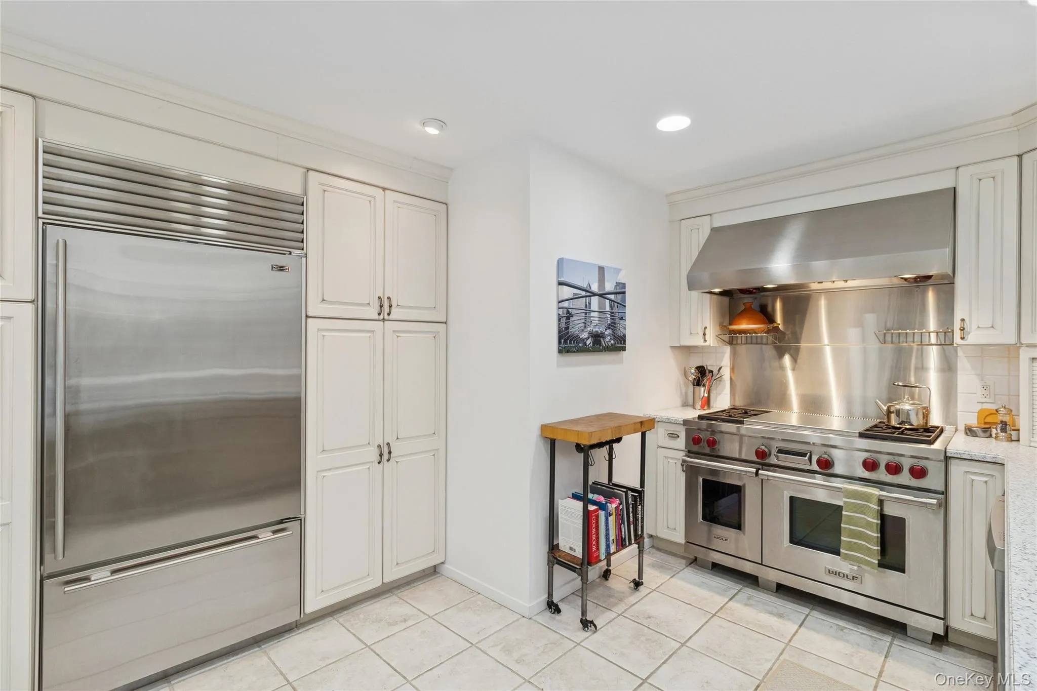 Kitchen featuring premium appliances, range hood, recessed lighting, light stone countertops, and backsplash Kitchen featuring premium appliances, range hood, recessed lighting, light stone countertops, and backsplash