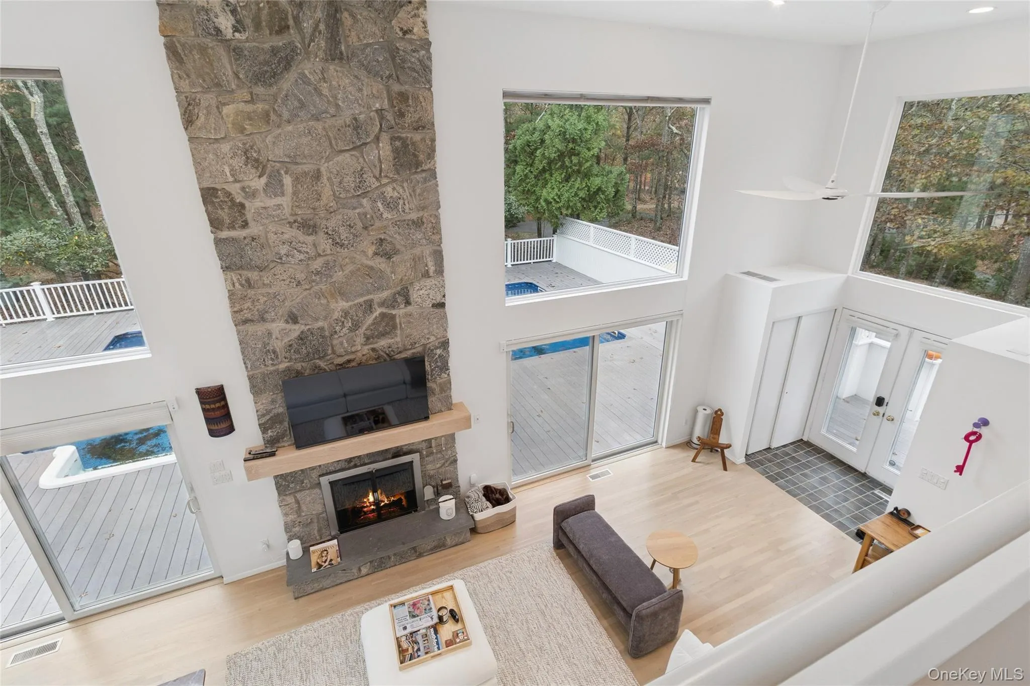 Living area featuring a towering ceiling, wood finished floors, a fireplace, and healthy amount of natural light Living area featuring a towering ceiling, wood finished floors, a fireplace, and healthy amount of natural light