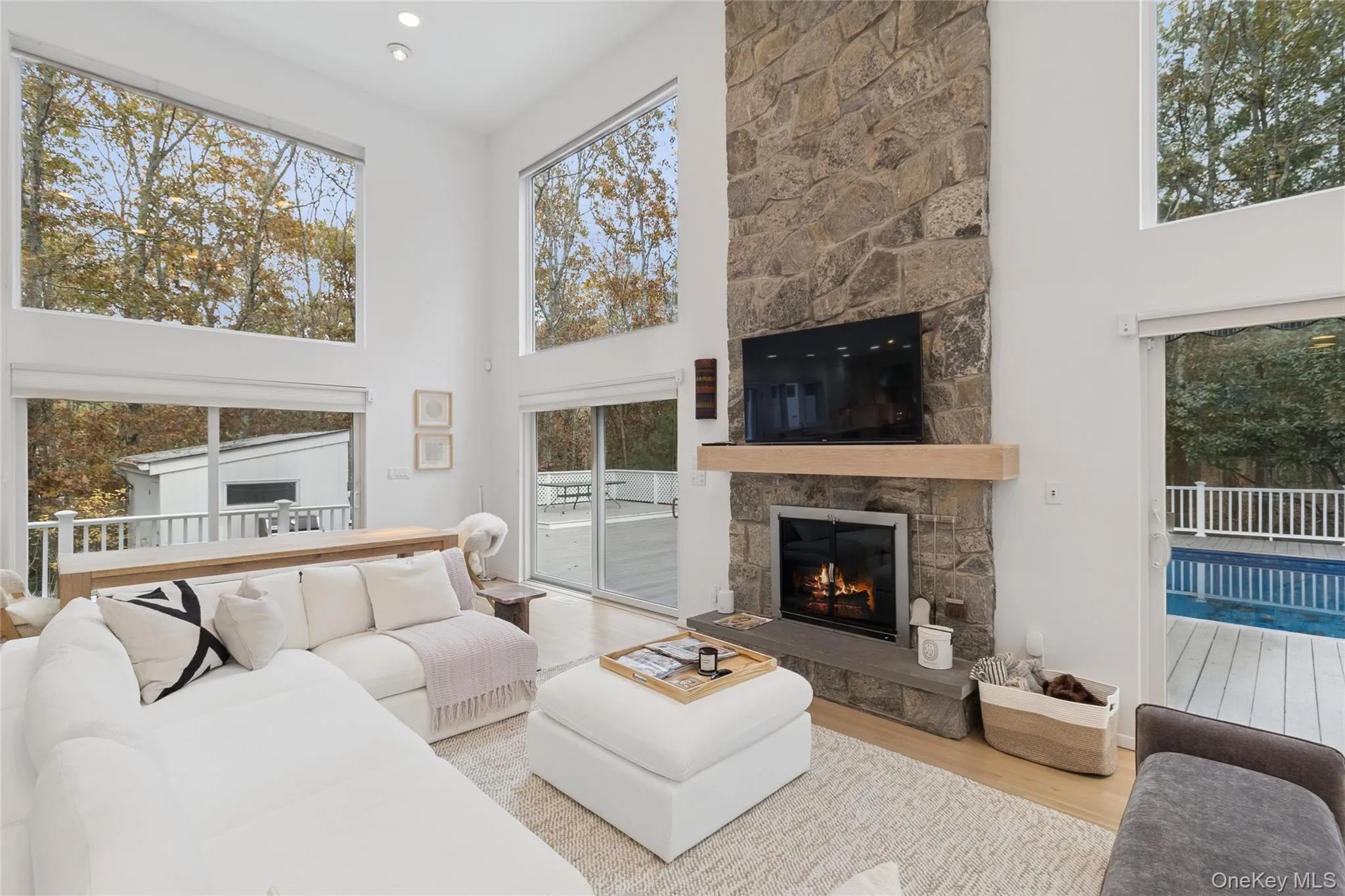 Living room featuring a towering ceiling, a stone fireplace, and wood finished floors Living room featuring a towering ceiling, a stone fireplace, and wood finished floors
