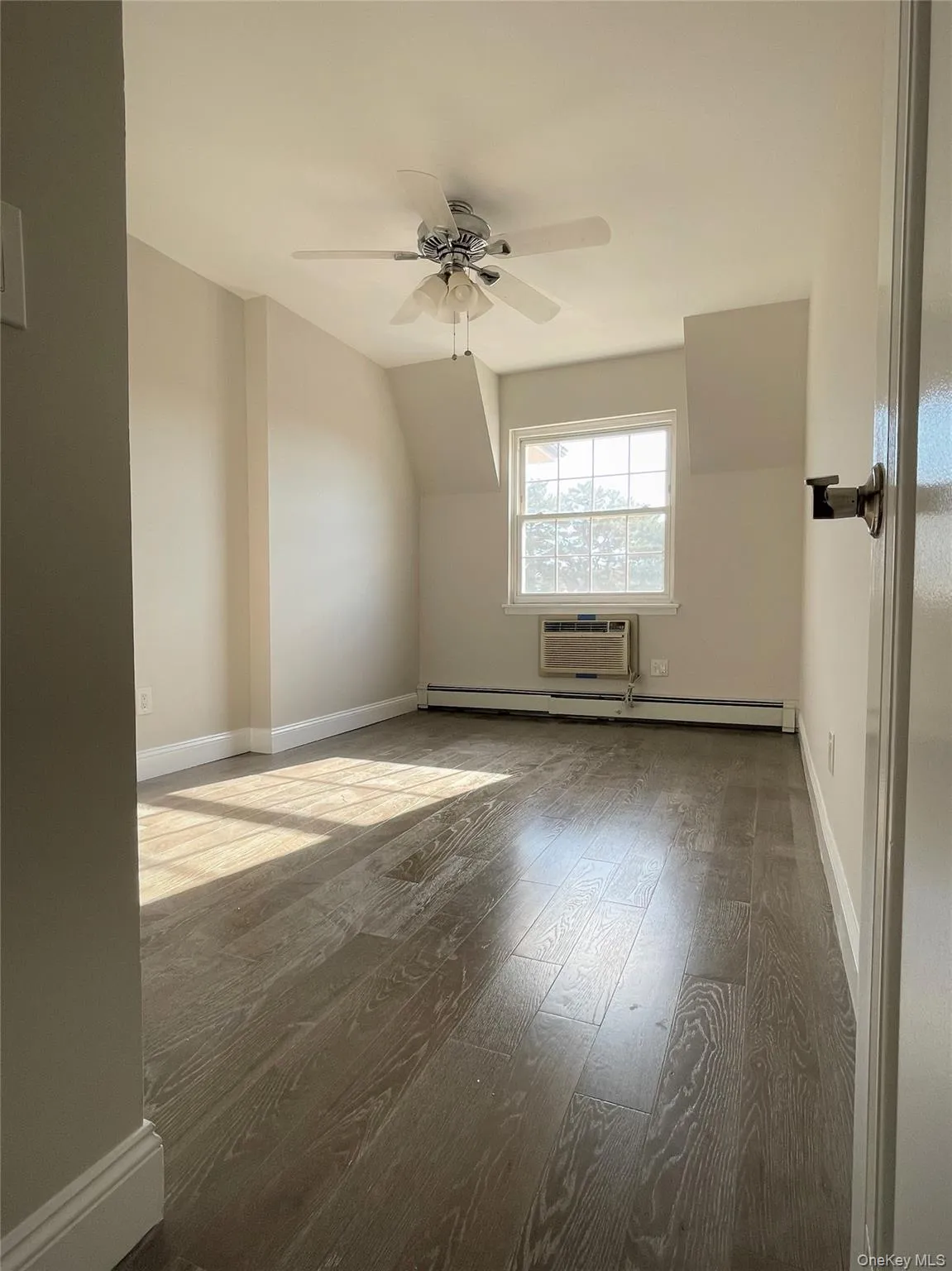 Bedroom 2 with wood finished floors, ceiling fan, a baseboard heating unit, and an AC wall unit Bedroom 2 with wood finished floors, ceiling fan, a baseboard heating unit, and an AC wall unit