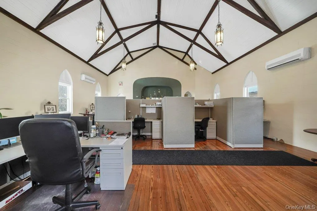 Office area with high vaulted ceiling, a wall unit AC, and beam ceiling Office area with high vaulted ceiling, a wall unit AC, and beam ceiling
