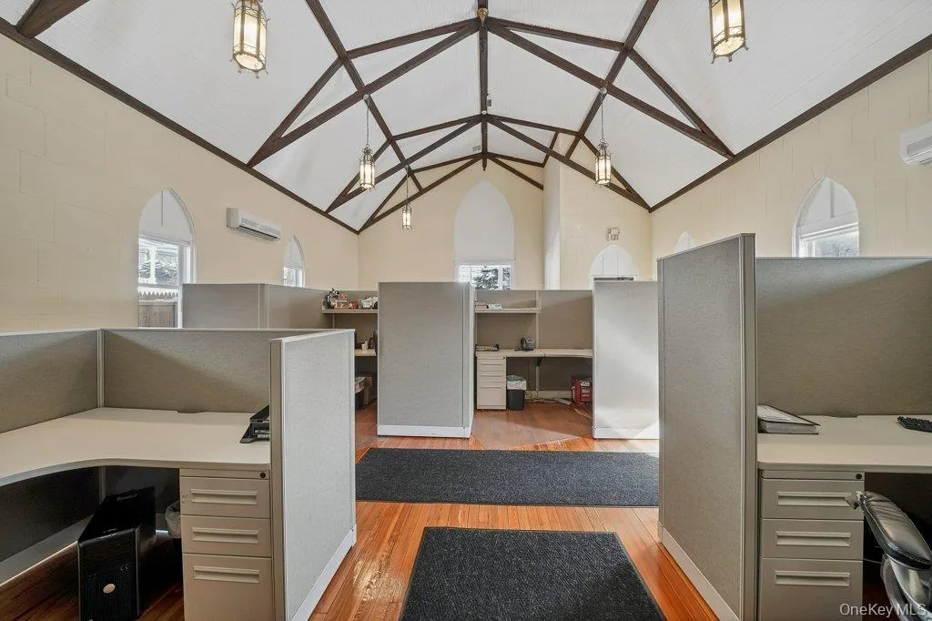 Professional office with high vaulted ceiling, wood finished floors, and built in study area Professional office with high vaulted ceiling, wood finished floors, and built in study area