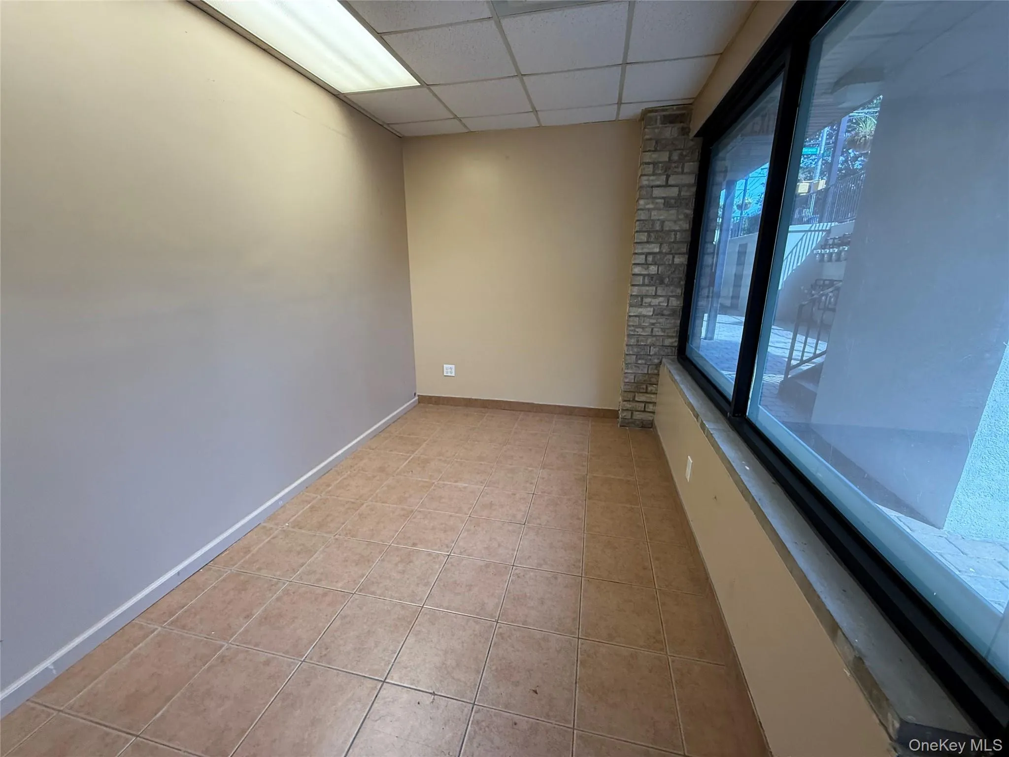 Spare room featuring a paneled ceiling and light tile patterned floors Spare room featuring a paneled ceiling and light tile patterned floors