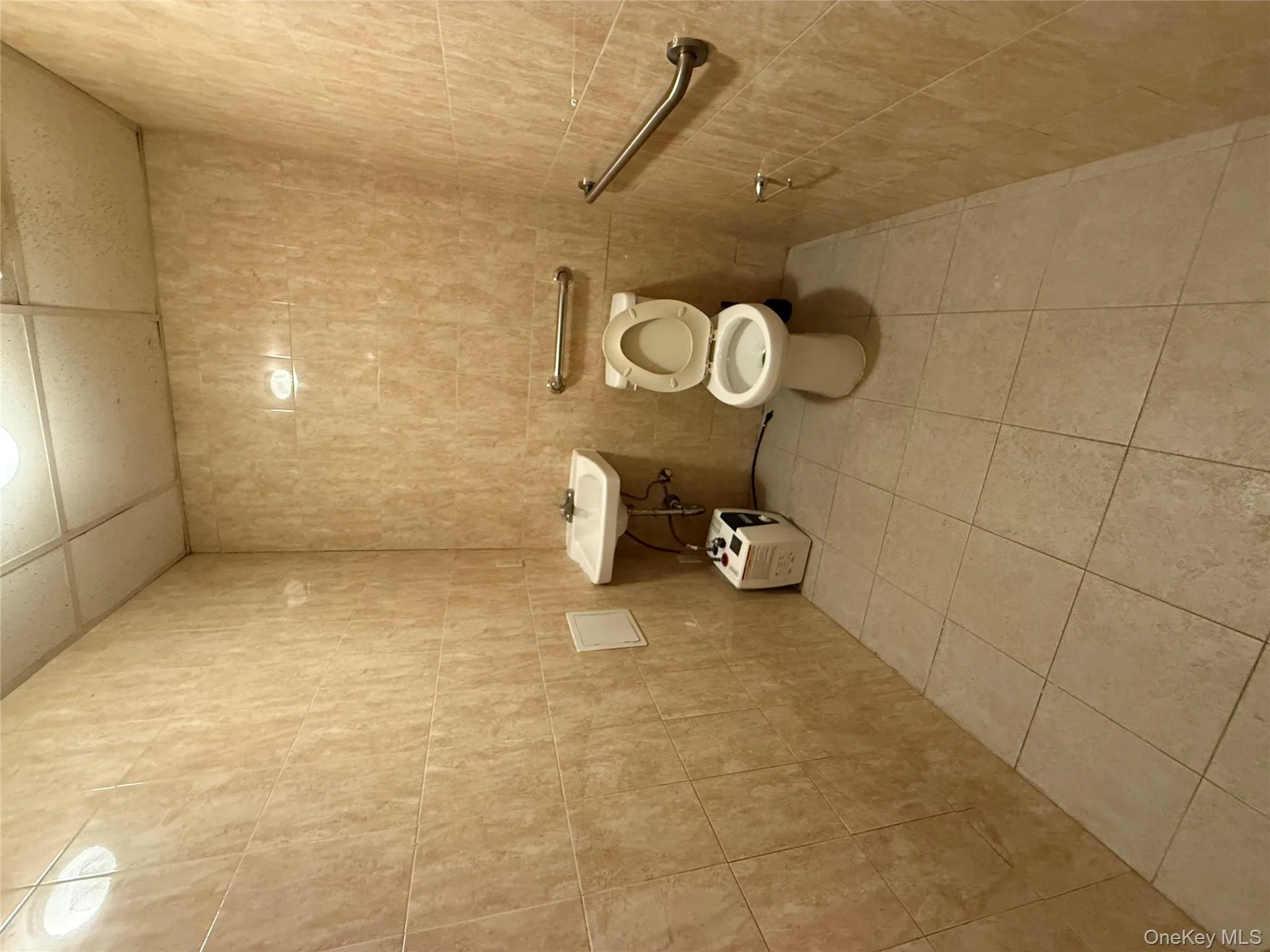 Bathroom featuring tile walls, light tile patterned floors, and a paneled ceiling Bathroom featuring tile walls, light tile patterned floors, and a paneled ceiling
