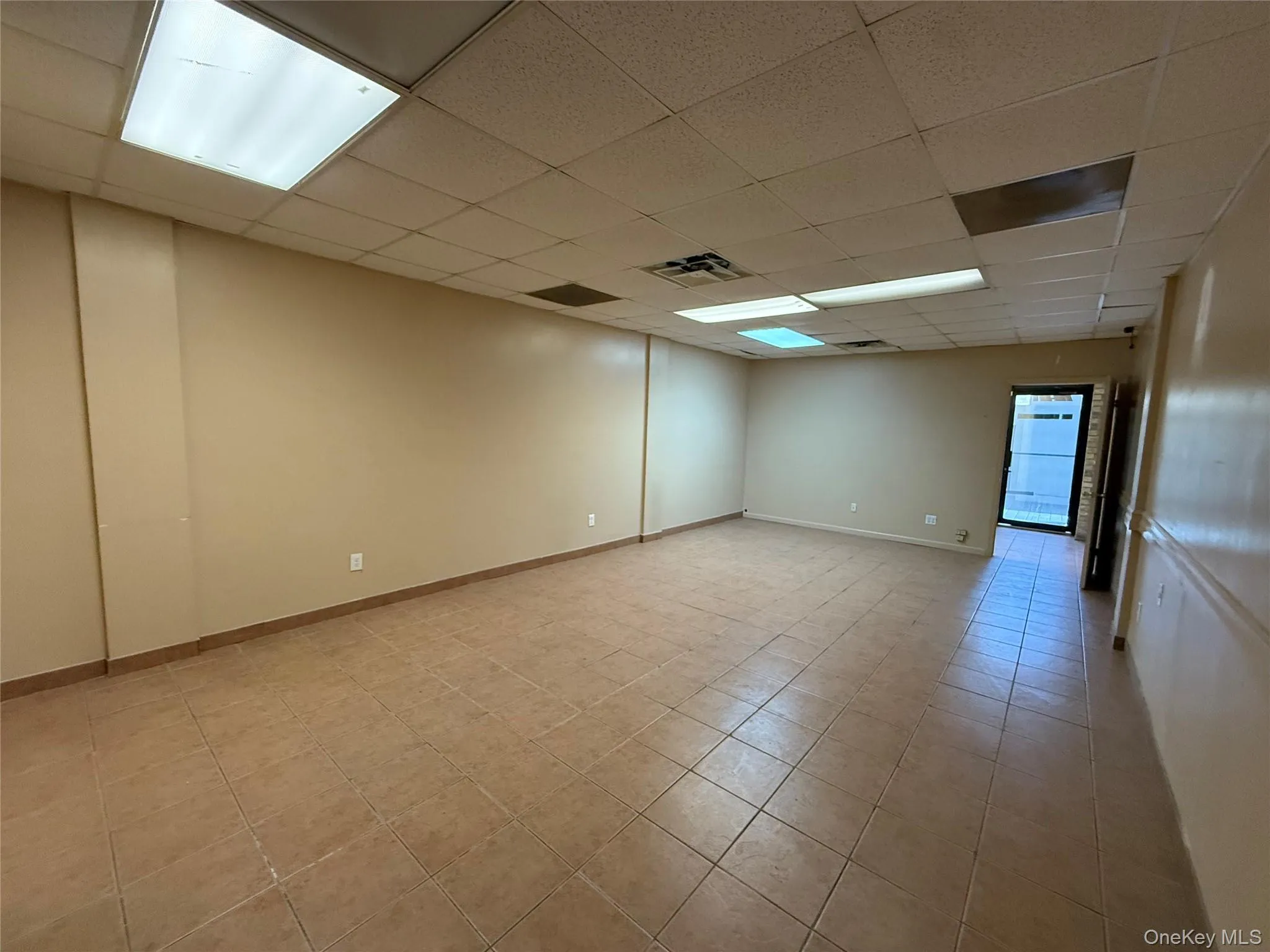 Empty room with a drop ceiling and light tile patterned flooring Empty room with a drop ceiling and light tile patterned flooring