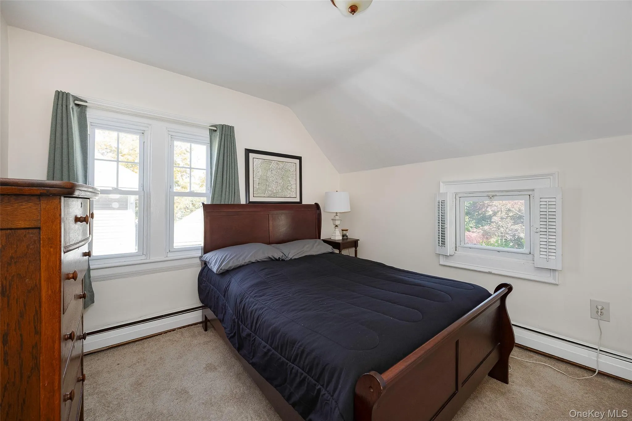 Bedroom with a baseboard heating unit, vaulted ceiling, and light carpet Bedroom with a baseboard heating unit, vaulted ceiling, and light carpet