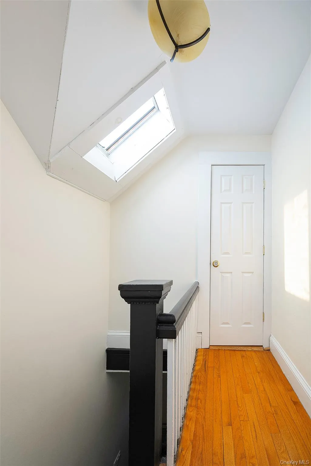 Hall with a skylight, light wood finished floors, and lofted ceiling Hall with a skylight, light wood finished floors, and lofted ceiling