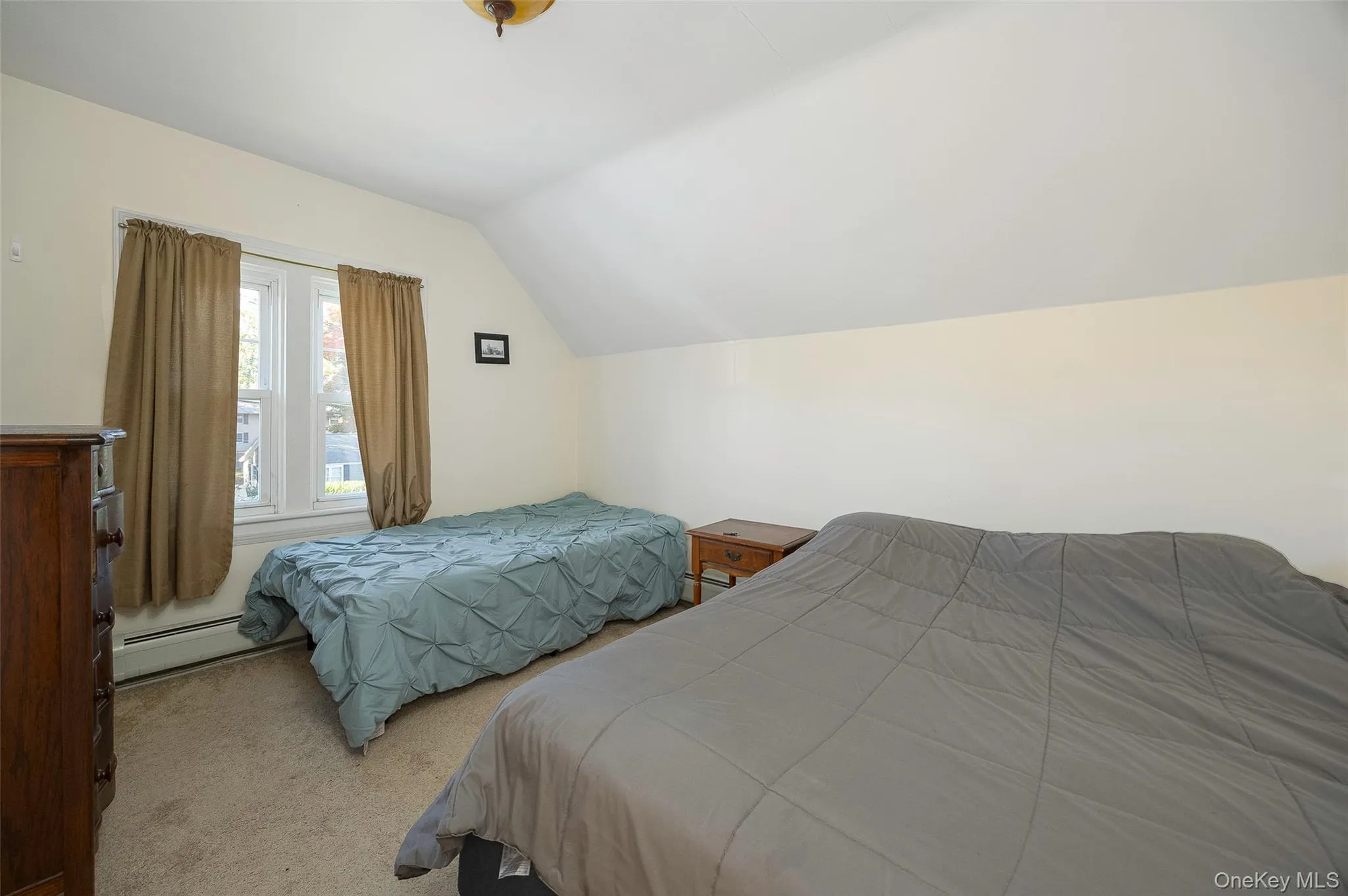 Bedroom with lofted ceiling, carpet flooring, and baseboard heating Bedroom with lofted ceiling, carpet flooring, and baseboard heating