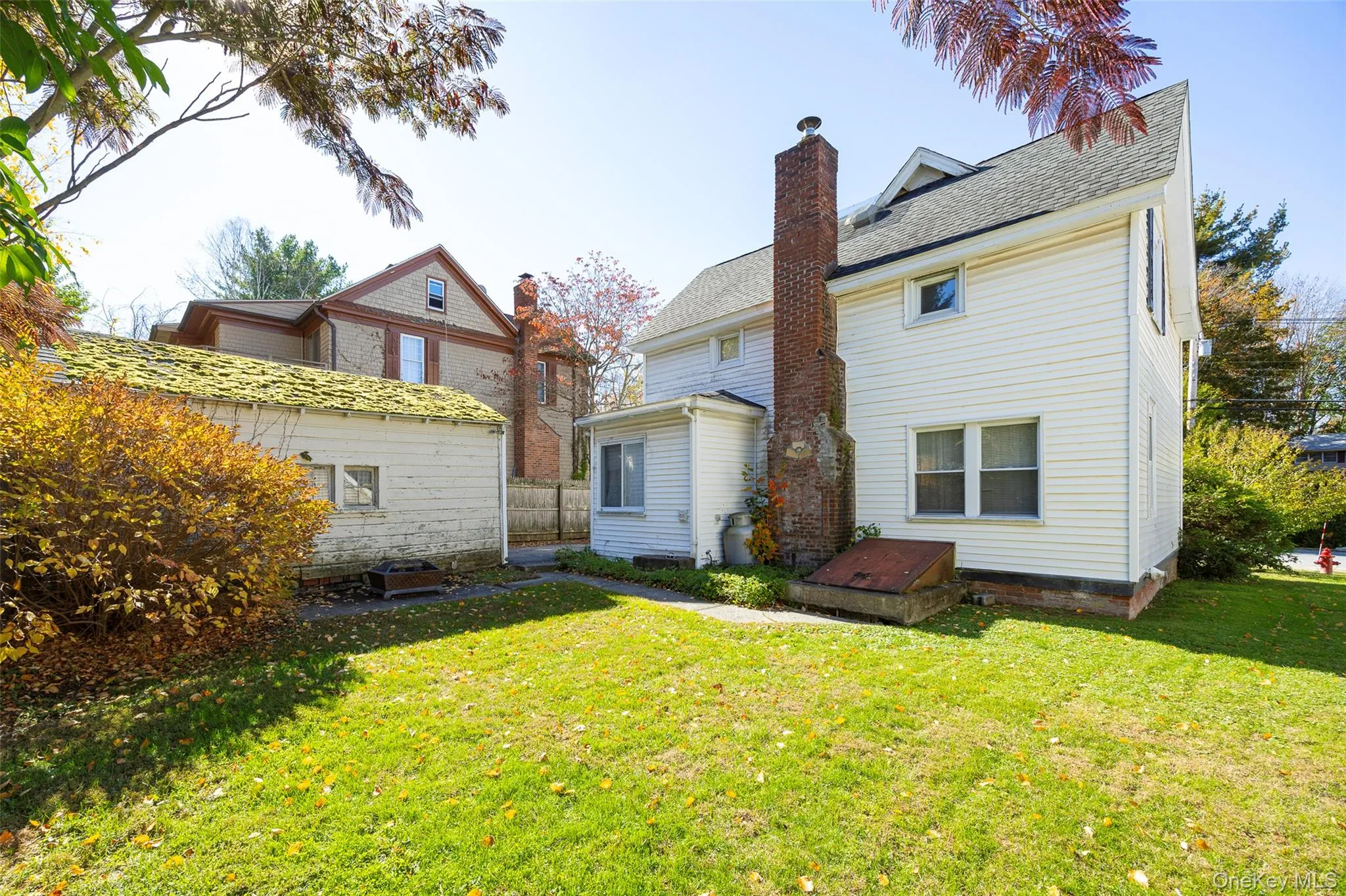 Back of house featuring a chimney, a lawn, and a shingled roof Back of house featuring a chimney, a lawn, and a shingled roof