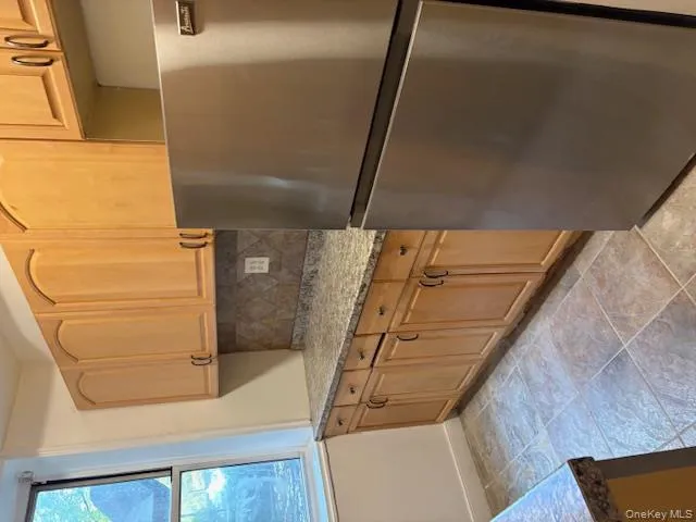 Kitchen with refrigerator, tasteful backsplash, light stone counters, and light tile patterned flooring Kitchen with refrigerator, tasteful backsplash, light stone counters, and light tile patterned flooring