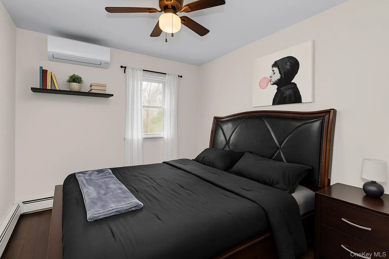 Bedroom with wood finished floors, a wall mounted air conditioner, ceiling fan, and baseboard heating Bedroom with wood finished floors, a wall mounted air conditioner, ceiling fan, and baseboard heating