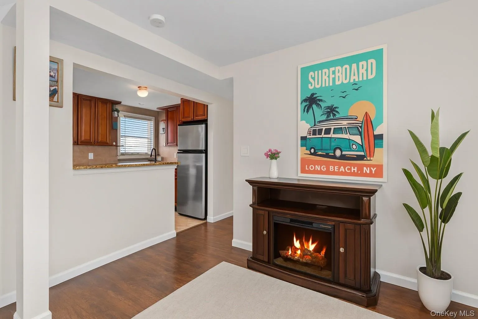Living room with dark wood-style flooring and a warm lit fireplace Living room with dark wood-style flooring and a warm lit fireplace