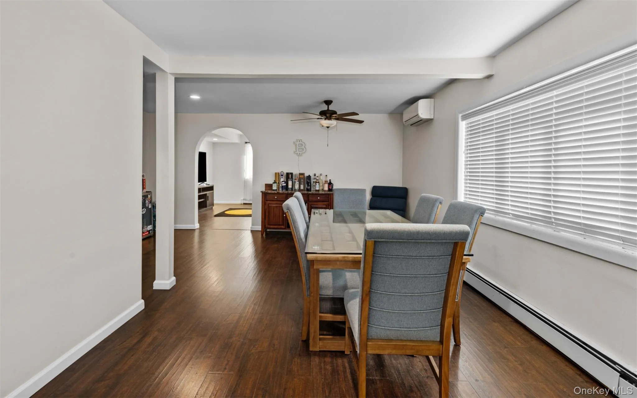 Dining space with a baseboard radiator, dark wood finished floors, arched walkways, ceiling fan, and an AC wall unit Dining space with a baseboard radiator, dark wood finished floors, arched walkways, ceiling fan, and an AC wall unit