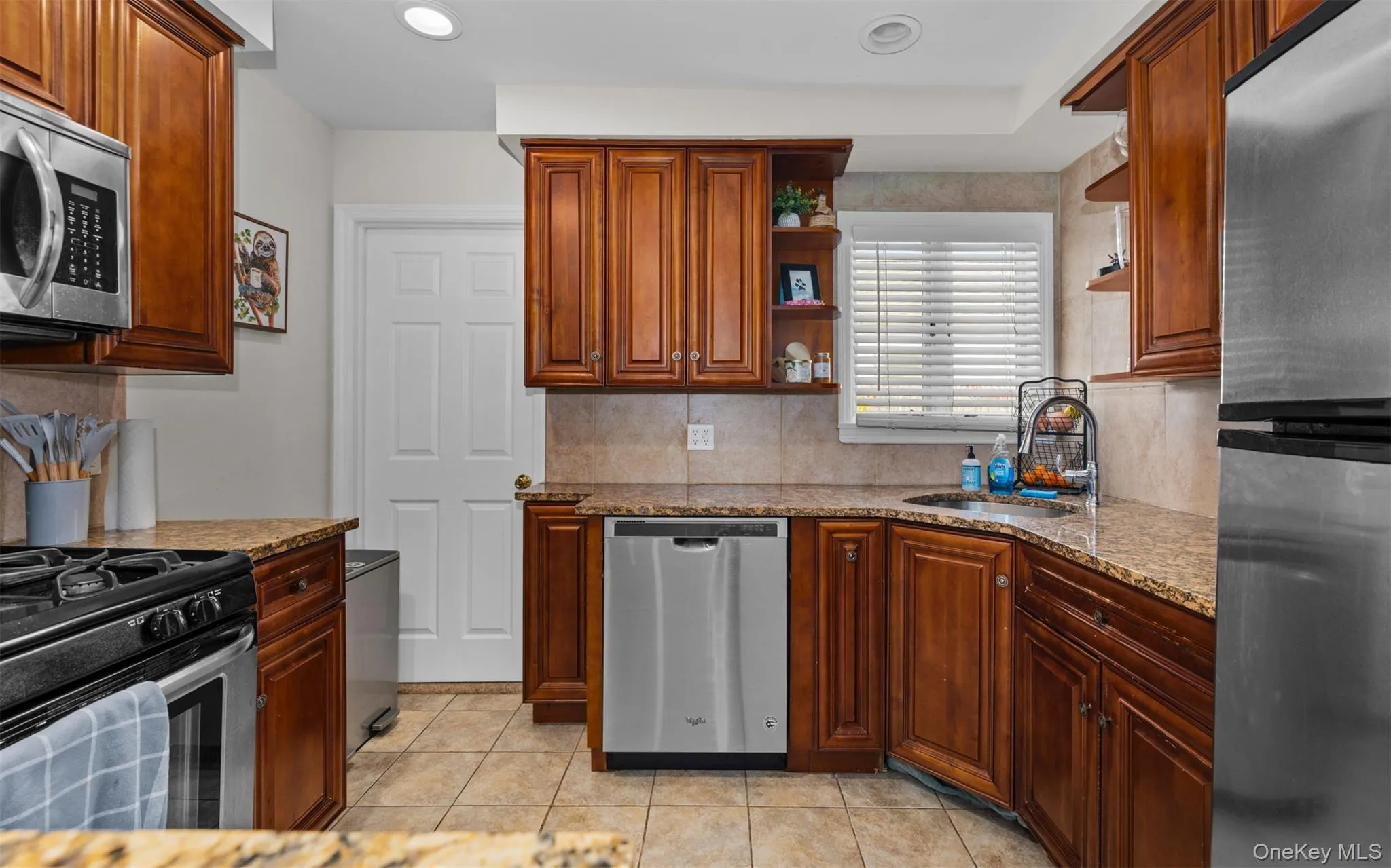 Kitchen with stainless steel appliances, open shelves, light tile patterned floors, light stone counters, and recessed lighting Kitchen with stainless steel appliances, open shelves, light tile patterned floors, light stone counters, and recessed lighting