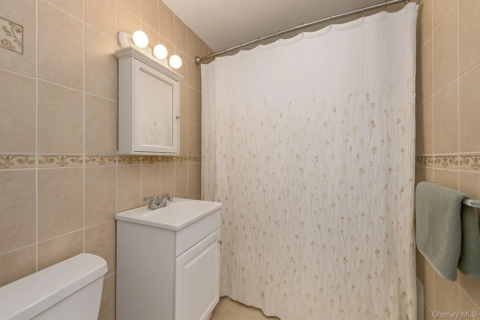 Bathroom with tile walls, a shower with curtain, vanity, and light tile patterned flooring Bathroom with tile walls, a shower with curtain, vanity, and light tile patterned flooring