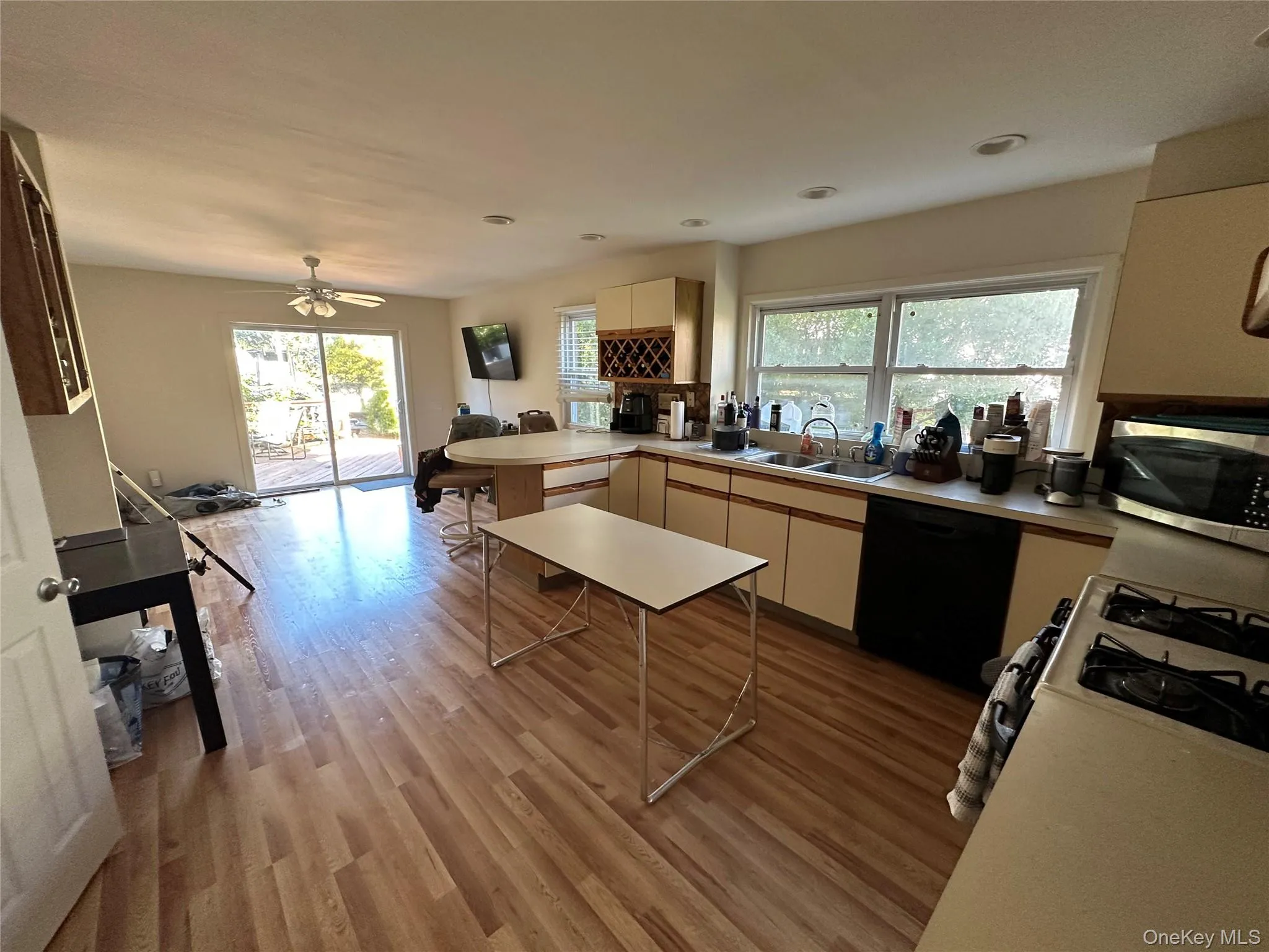 Kitchen with black dishwasher, white gas range, light wood-style floors, light countertops, and stainless steel microwave Kitchen with black dishwasher, white gas range, light wood-style floors, light countertops, and stainless steel microwave