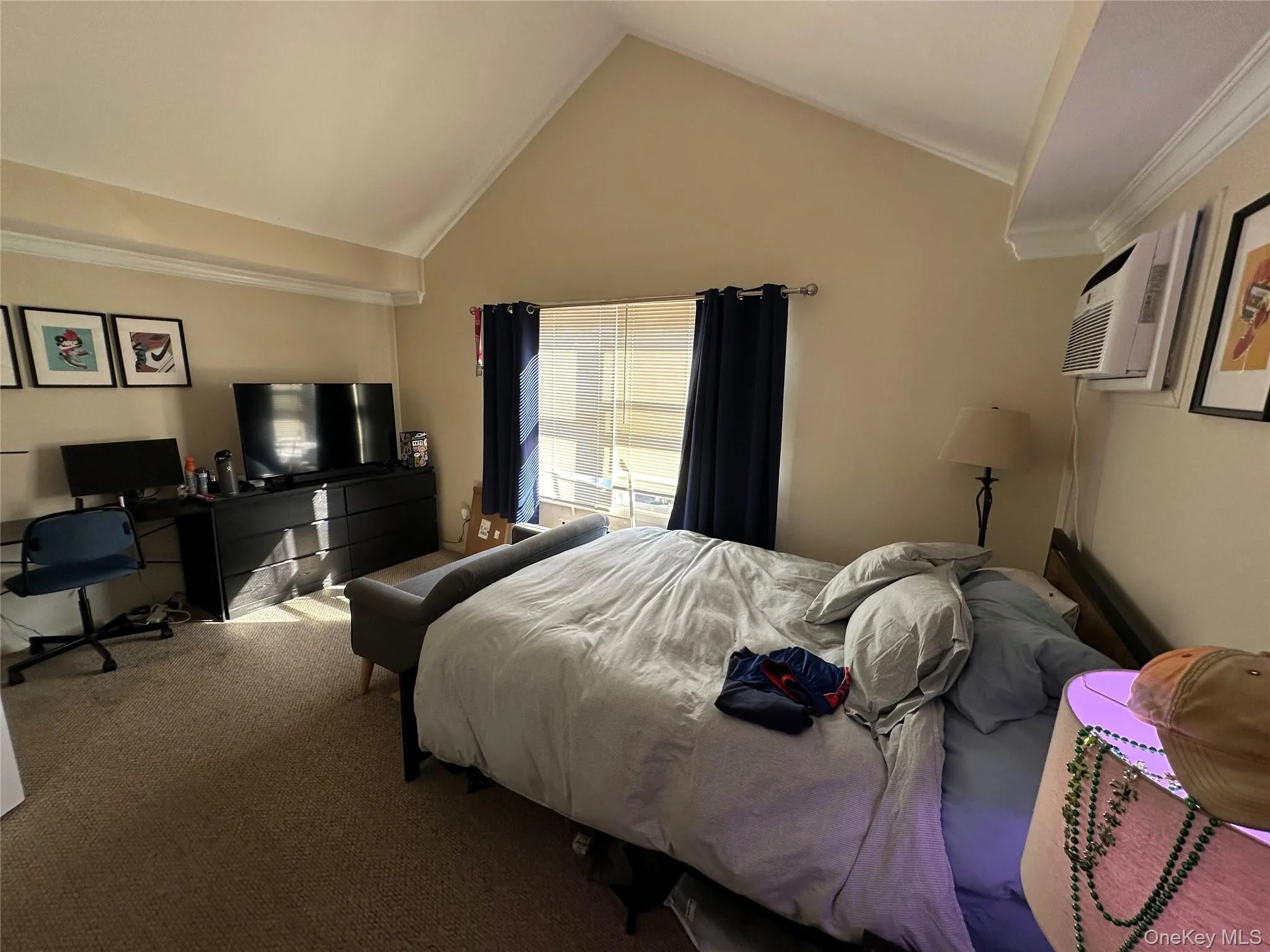 Bedroom with carpet floors, vaulted ceiling, ornamental molding, a desk, and a wall mounted AC Bedroom with carpet floors, vaulted ceiling, ornamental molding, a desk, and a wall mounted AC