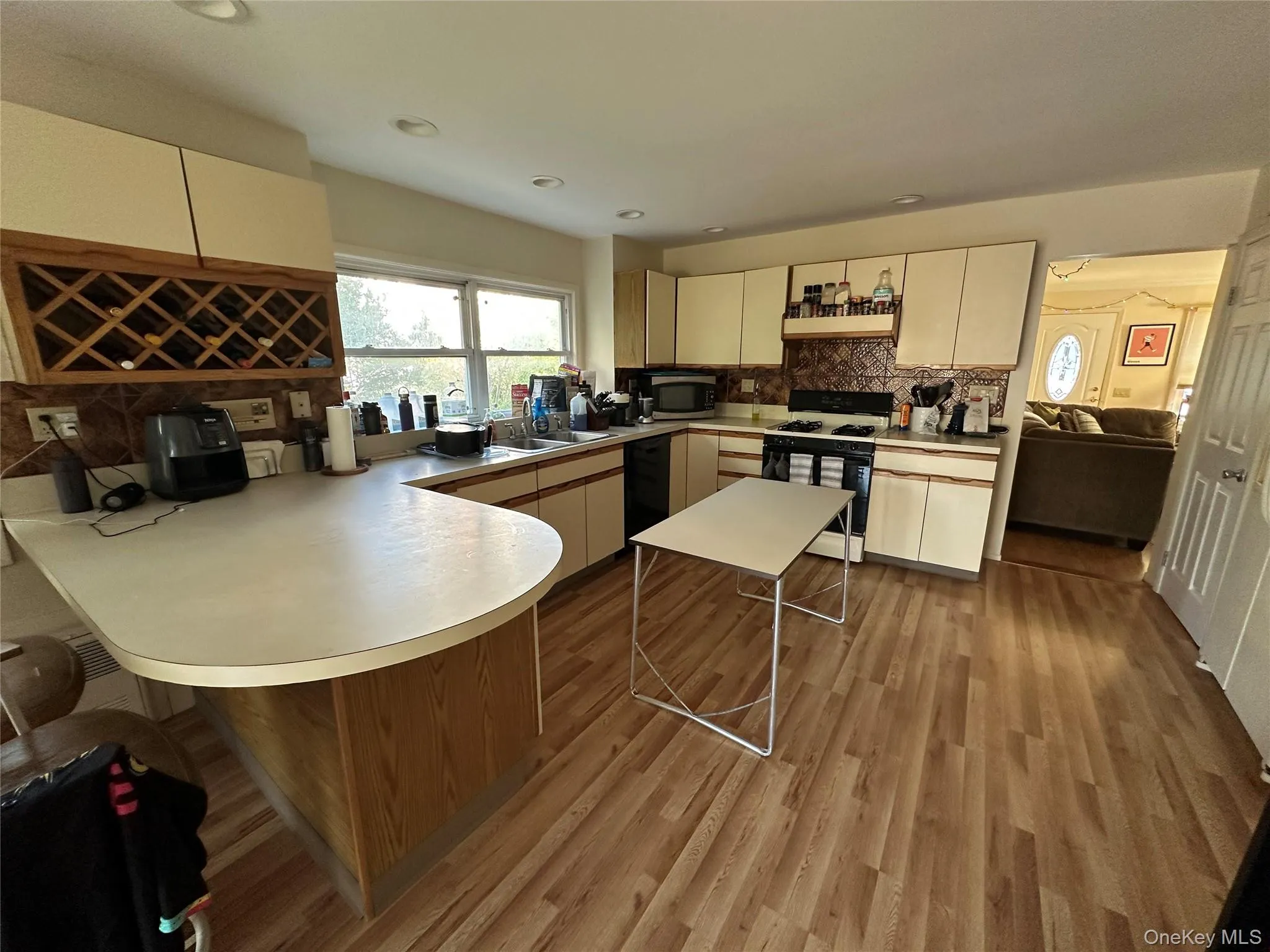 Kitchen with a peninsula, a breakfast bar, light countertops, gas range oven, and light wood-style flooring Kitchen with a peninsula, a breakfast bar, light countertops, gas range oven, and light wood-style flooring