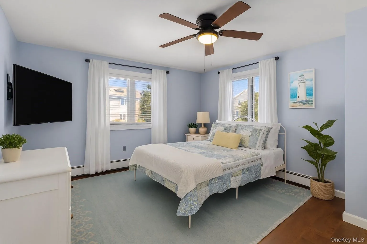 Bedroom featuring dark wood finished floors, a ceiling fan, and a baseboard radiator Bedroom featuring dark wood finished floors, a ceiling fan, and a baseboard radiator