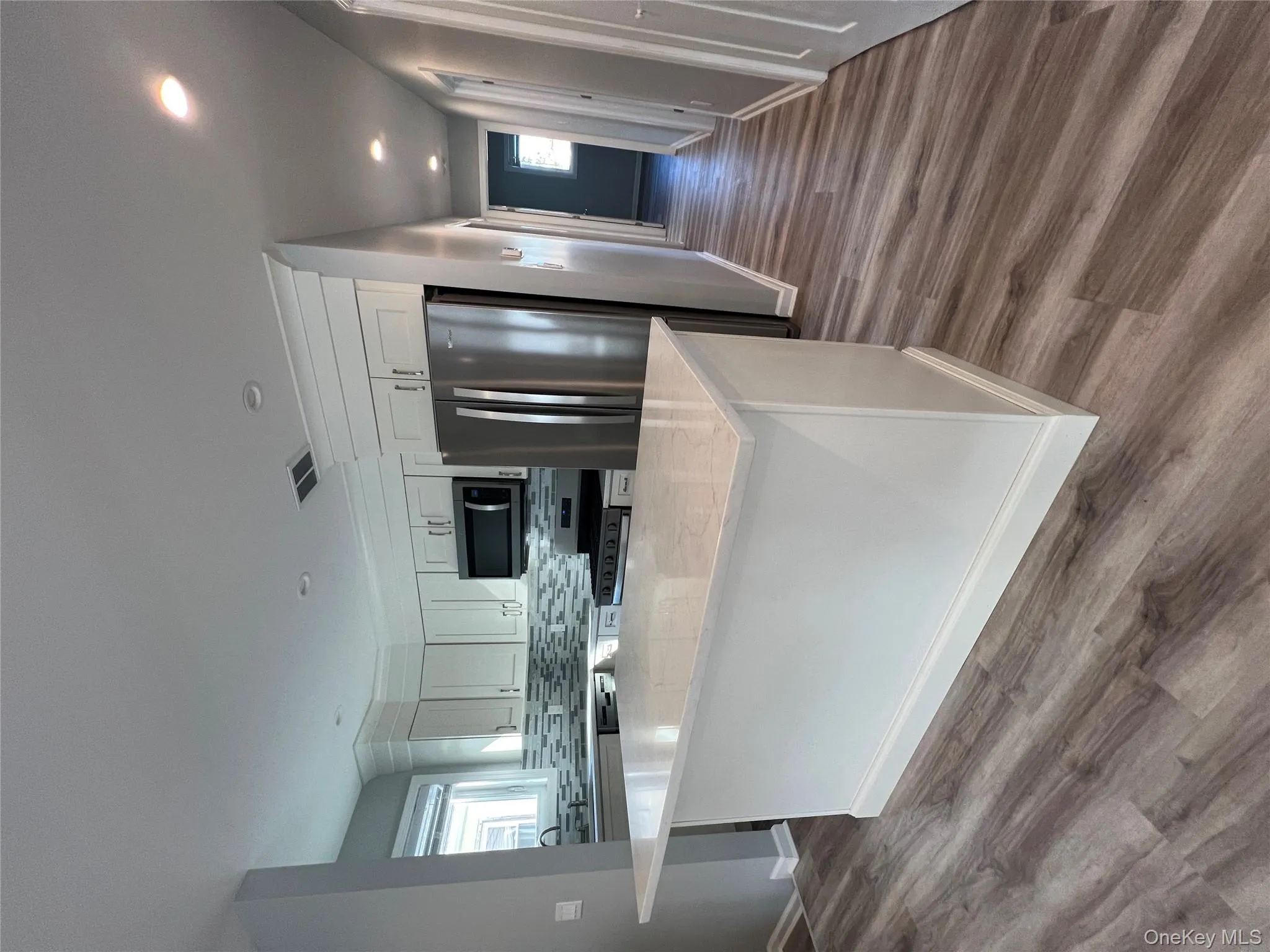 Kitchen with light stone countertops, white cabinetry, appliances with stainless steel finishes, backsplash, and a kitchen island Kitchen with light stone countertops, white cabinetry, appliances with stainless steel finishes, backsplash, and a kitchen island